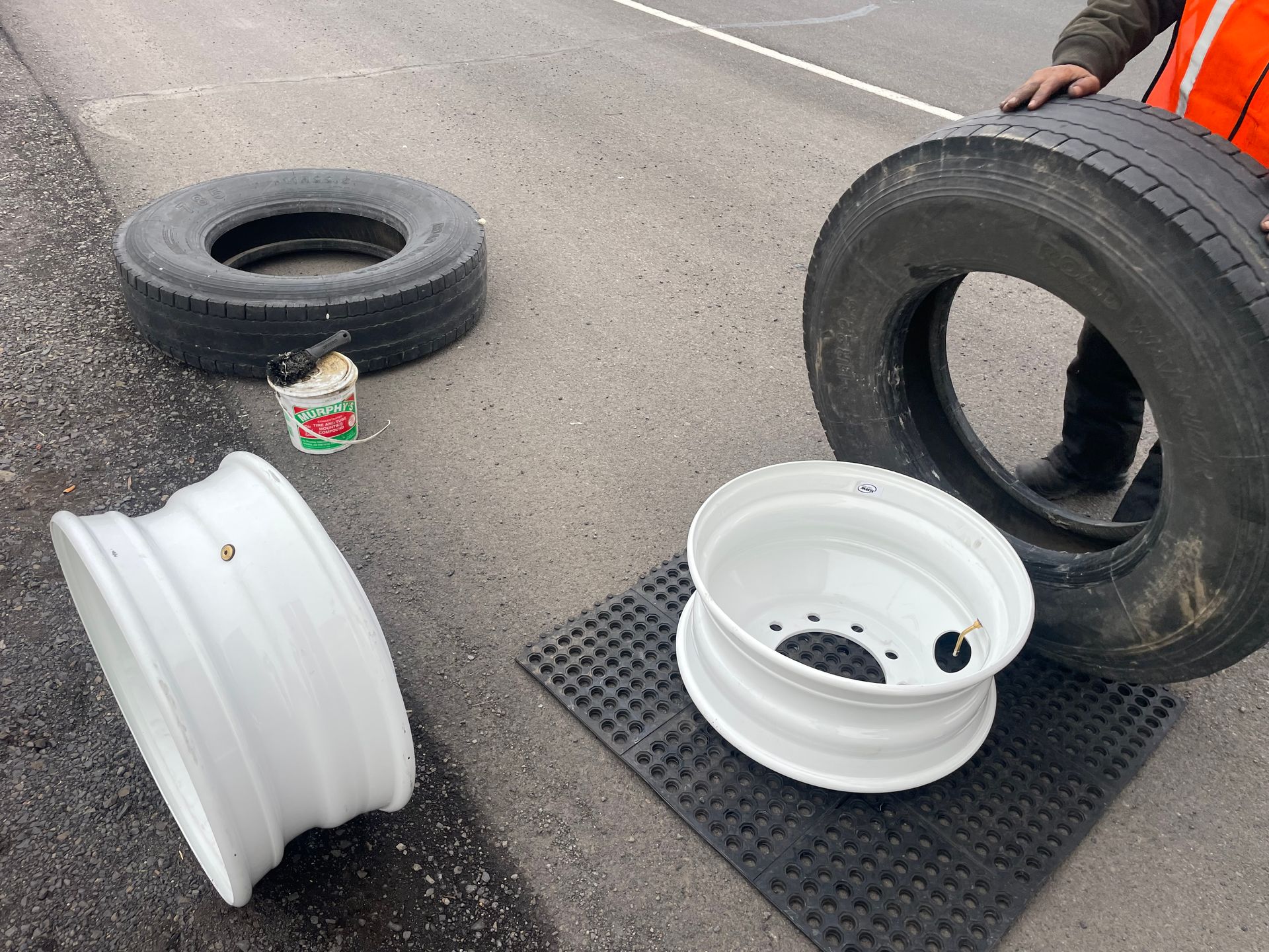 A man is standing next to a tire and a wheel on the side of the road.