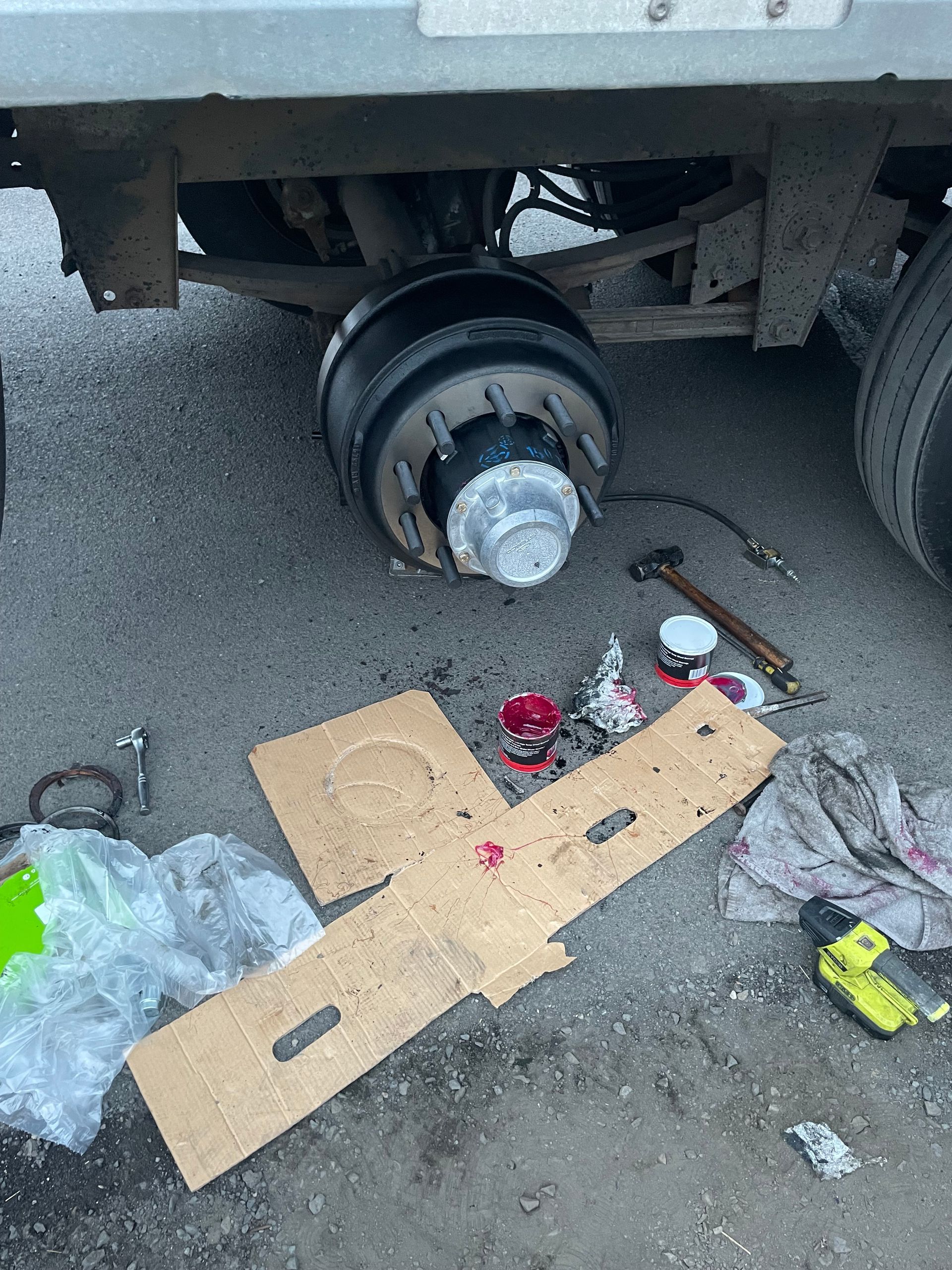 A truck with a broken wheel is being repaired on the ground.