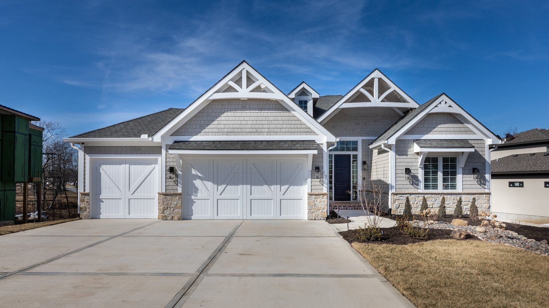 A large white house with a large garage and a concrete driveway.