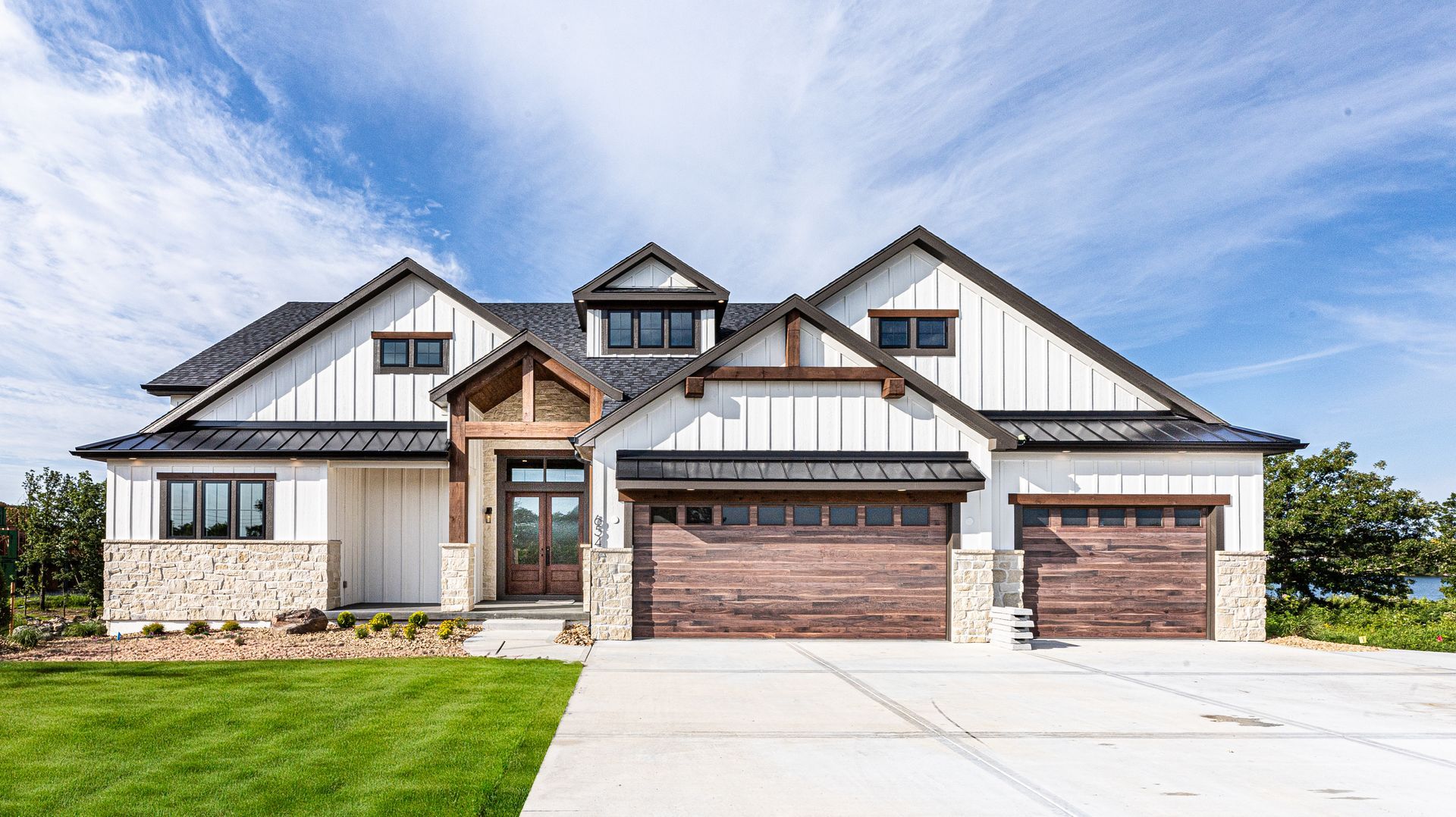A large white and brown house with two garages and a driveway.