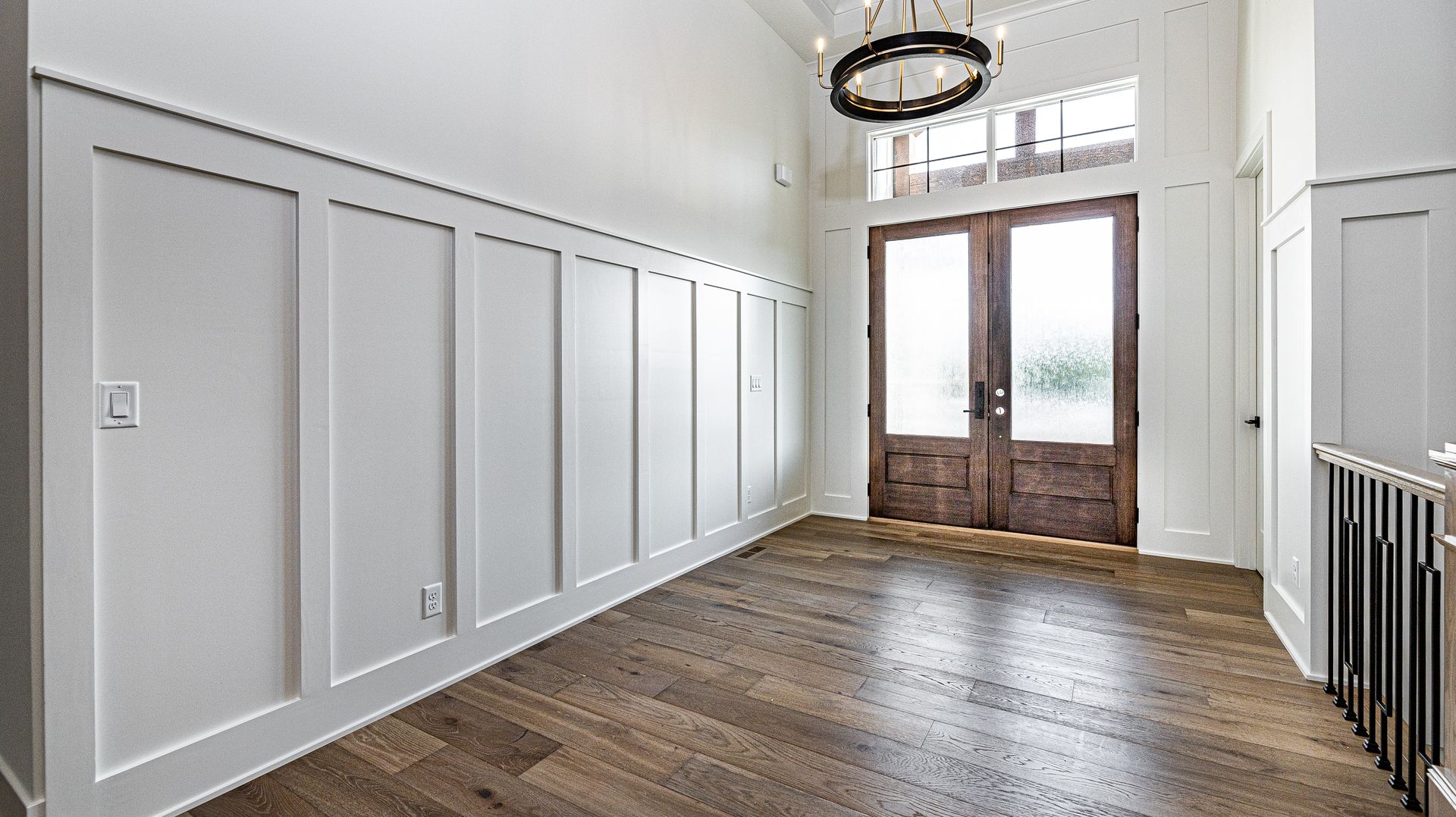 A large empty room with hardwood floors and a wooden door.