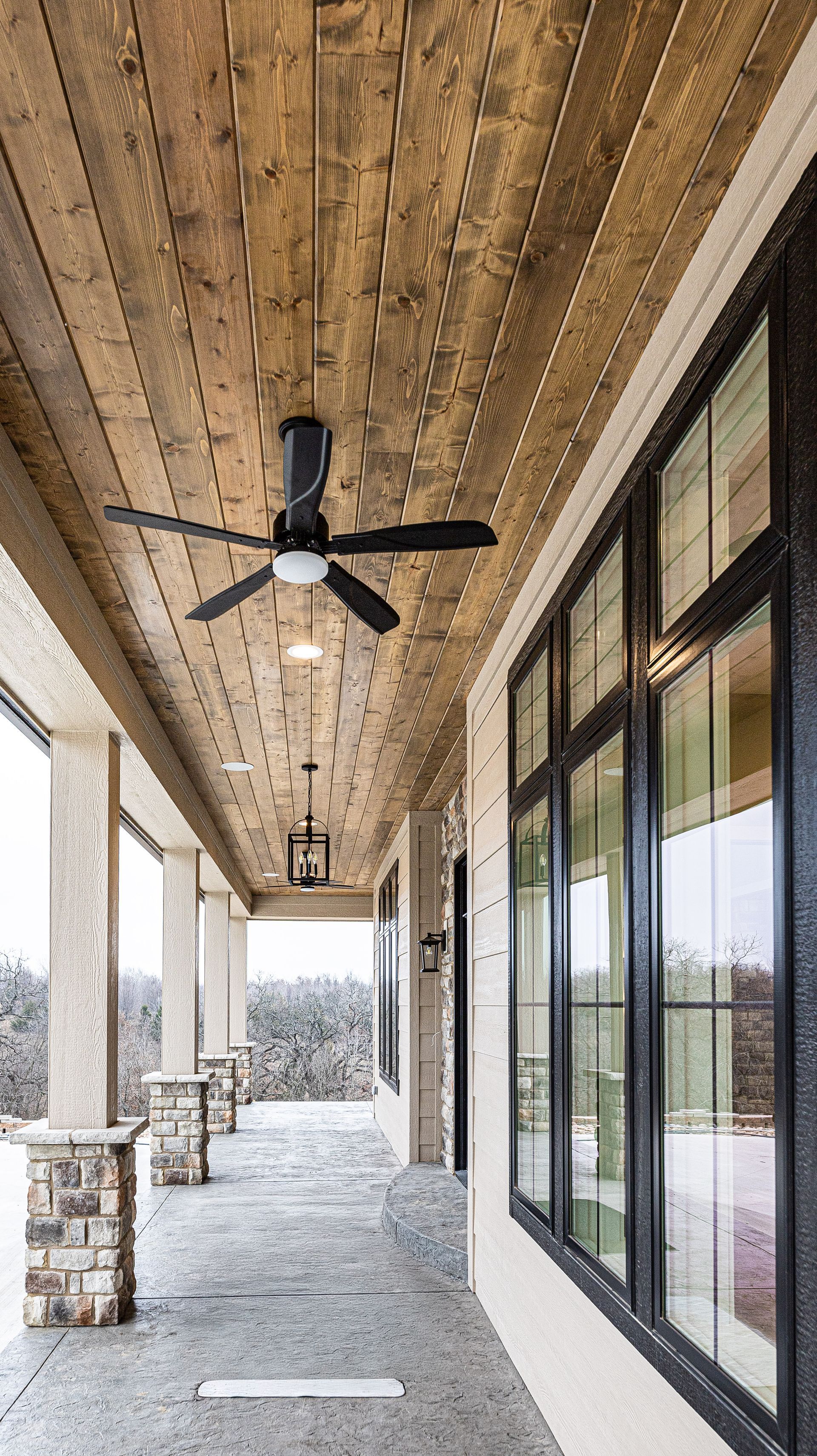 A long porch with a ceiling fan hanging from the ceiling.
