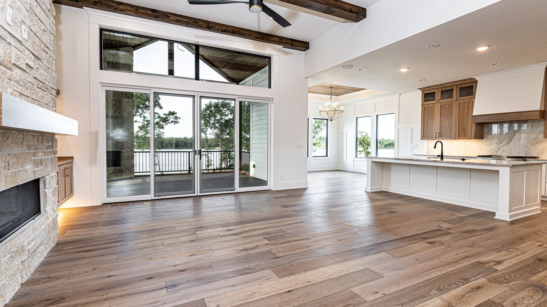 An empty living room with hardwood floors and sliding glass doors leading to a kitchen.