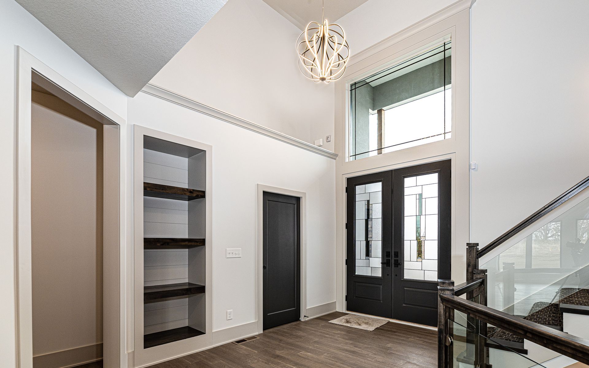 A large hallway with a staircase and a chandelier hanging from the ceiling.