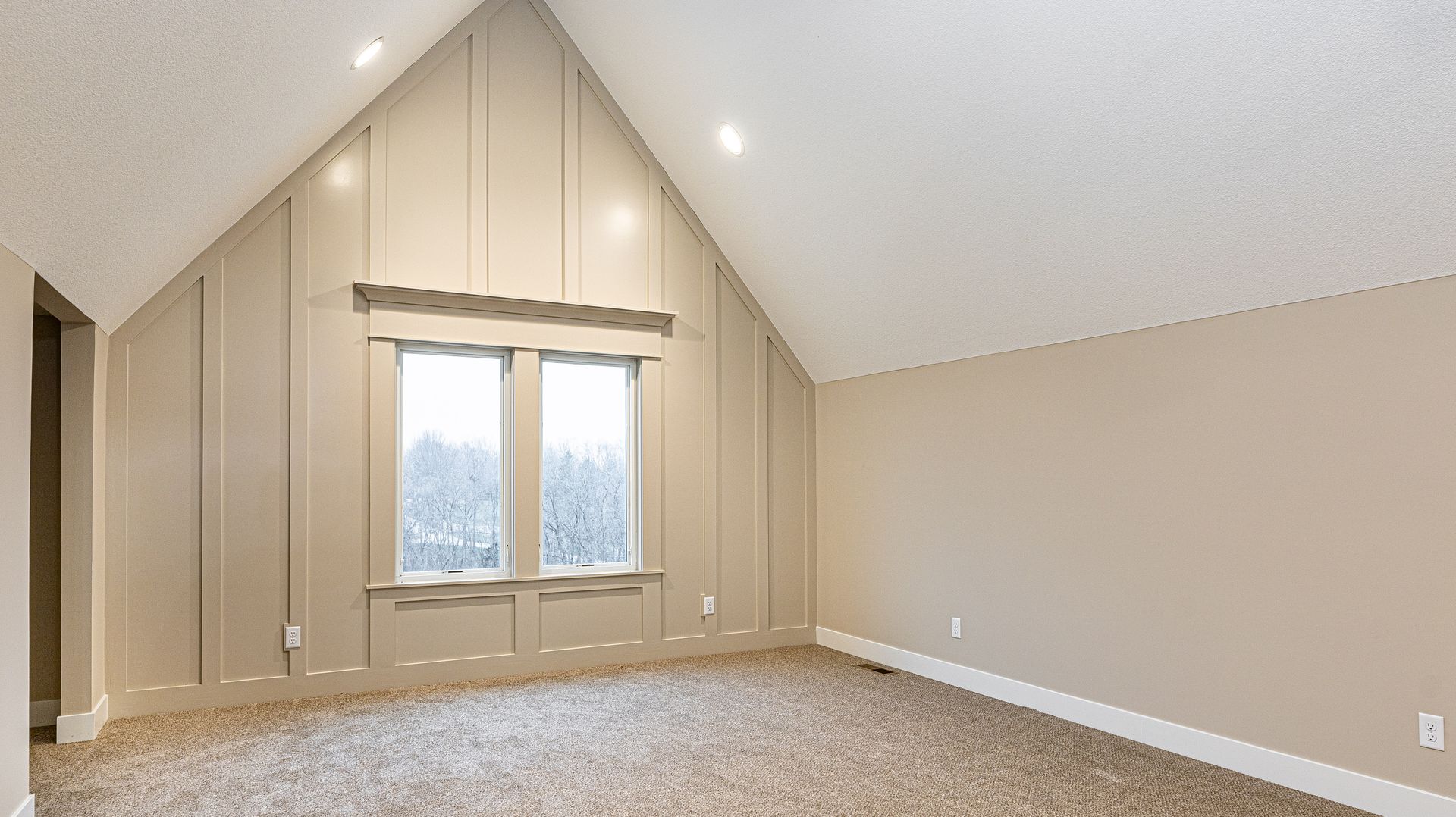 An empty room with a vaulted ceiling and two windows.