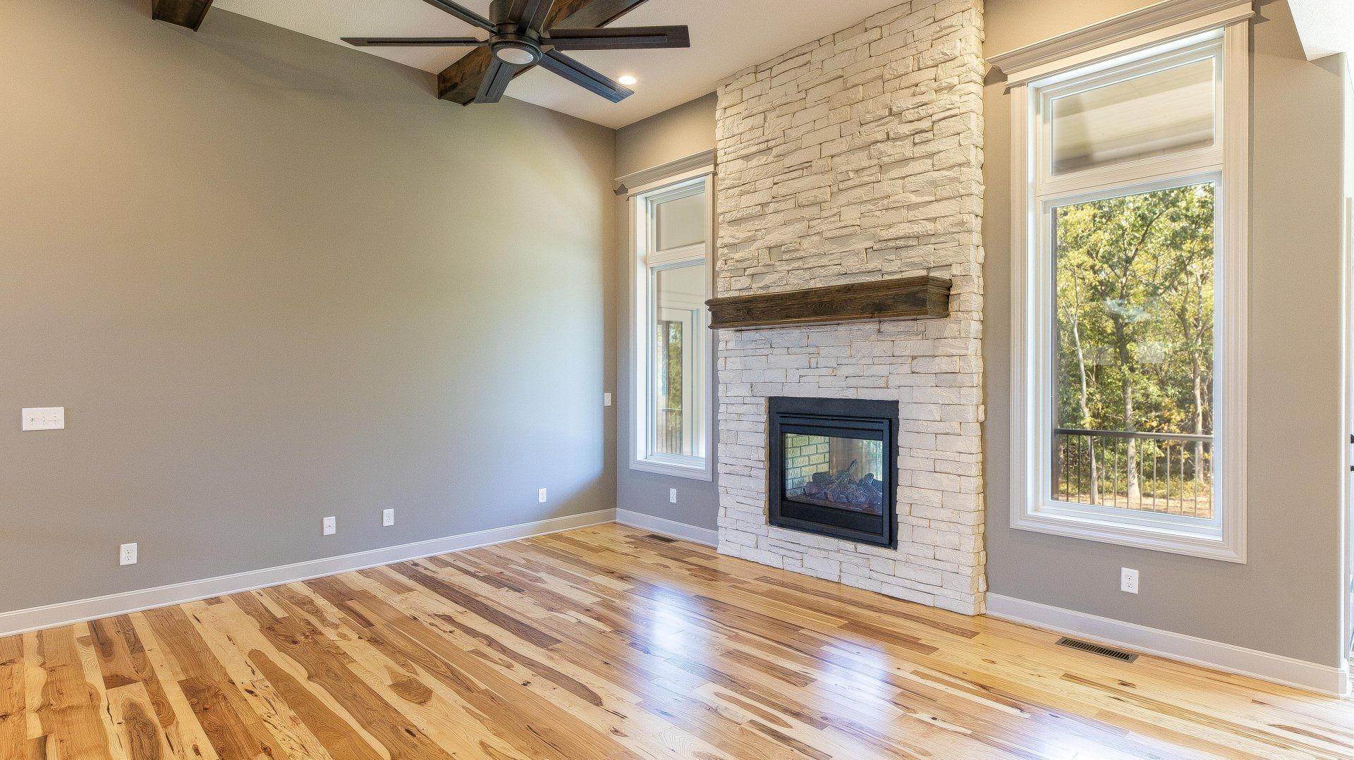 An empty living room with hardwood floors and a fireplace.
