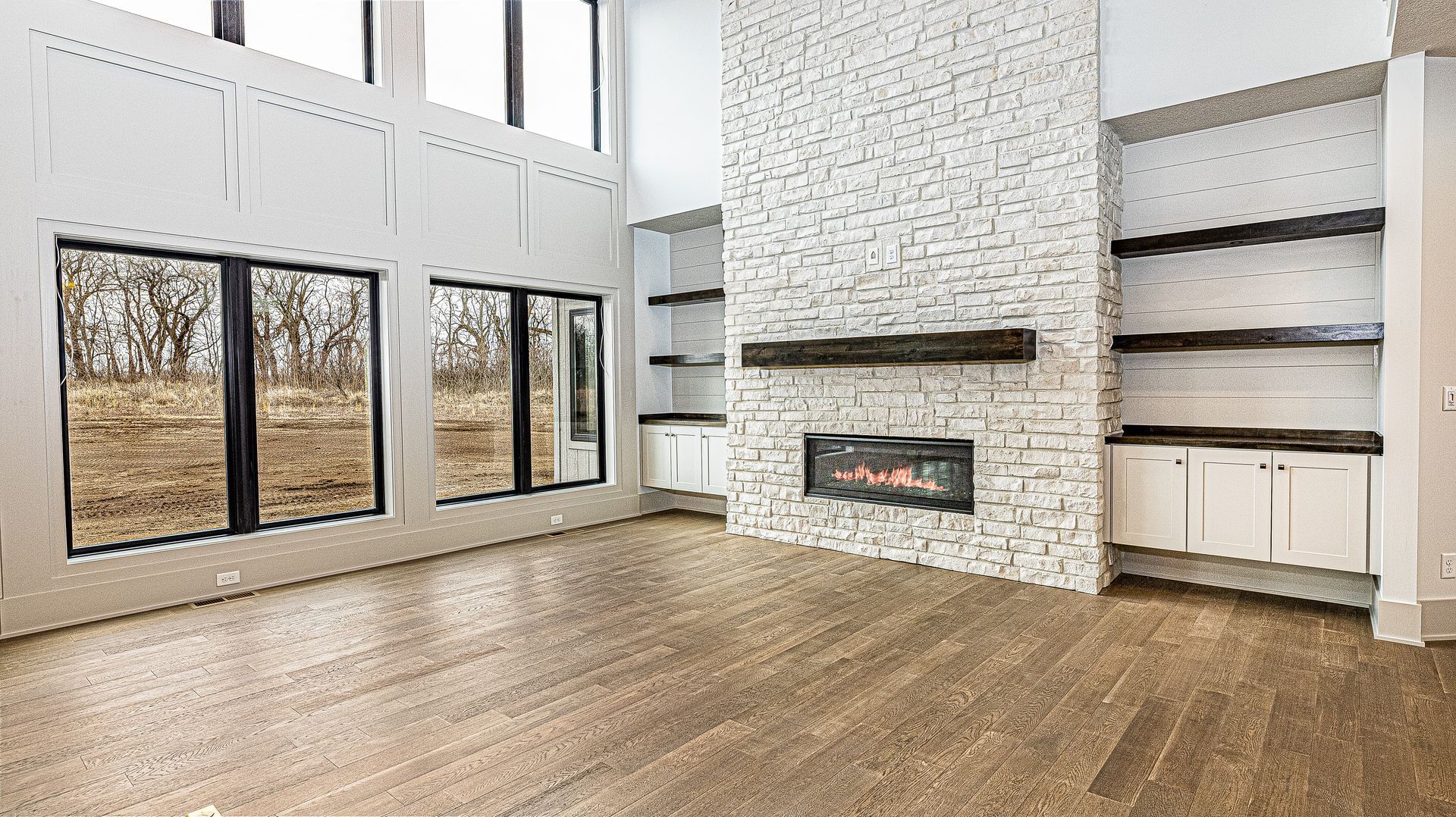 An empty living room with a fireplace and lots of windows.