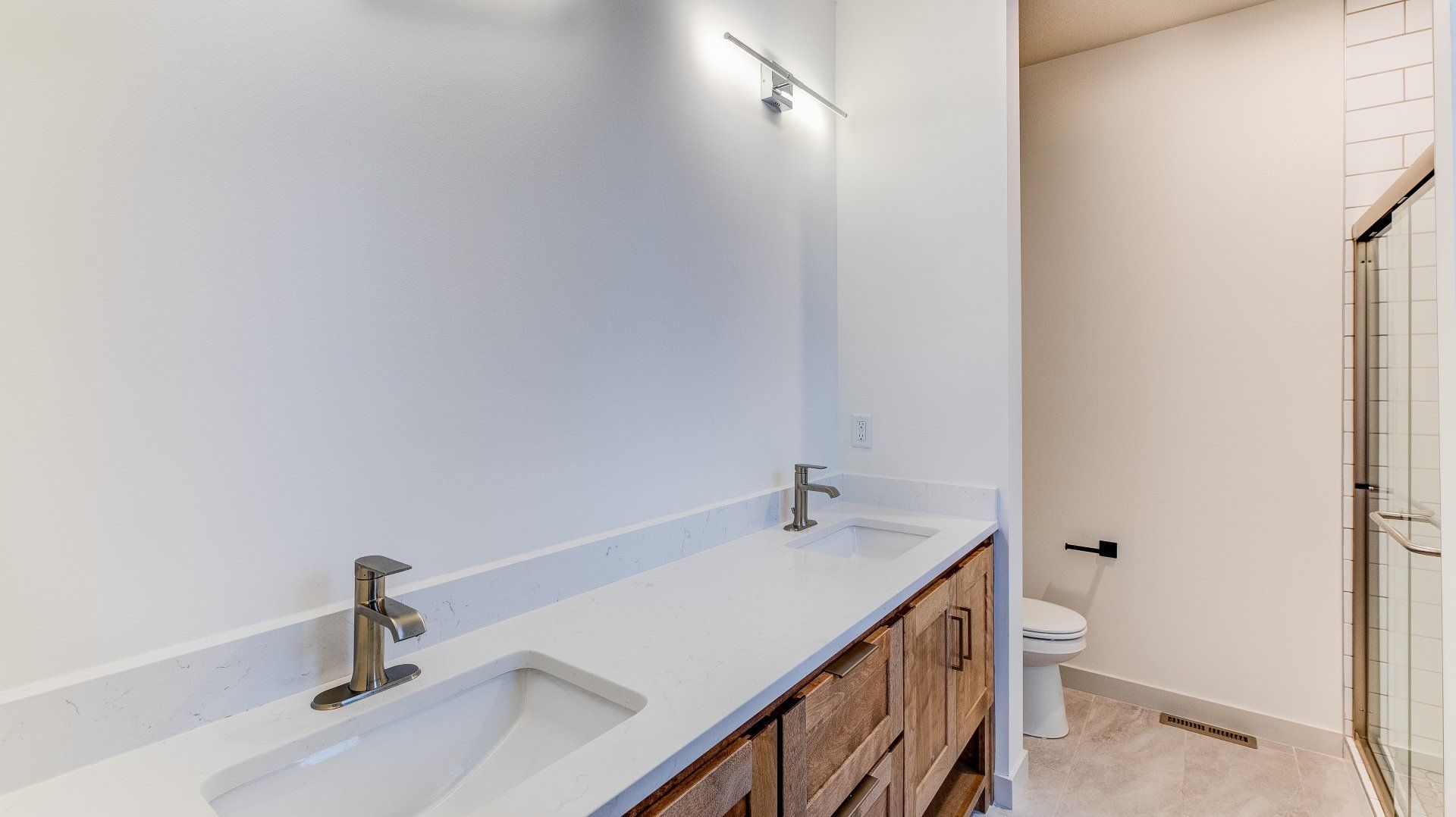 A bathroom with two sinks , a toilet and a shower.