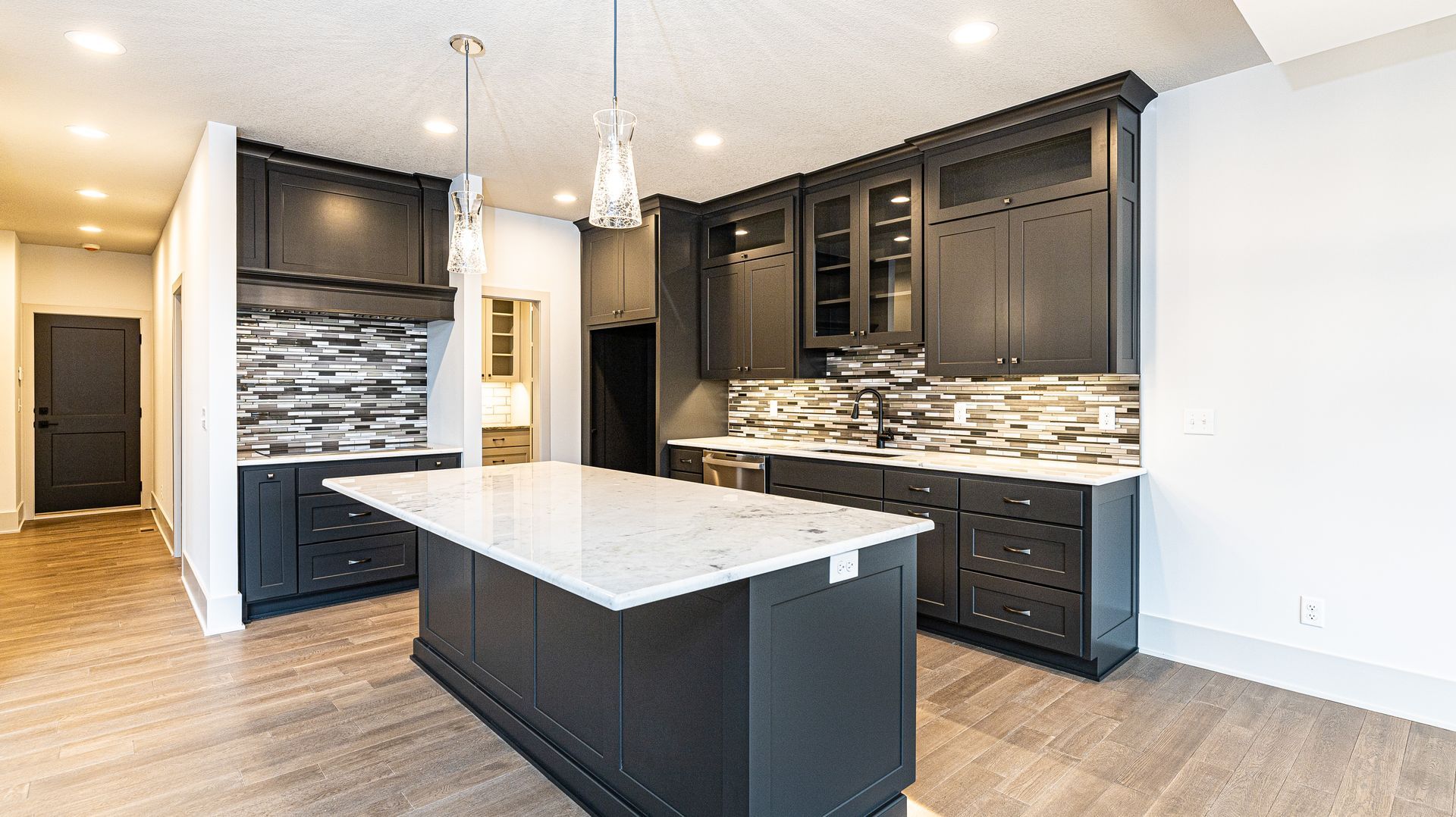 A kitchen with black cabinets and a large island in the middle.