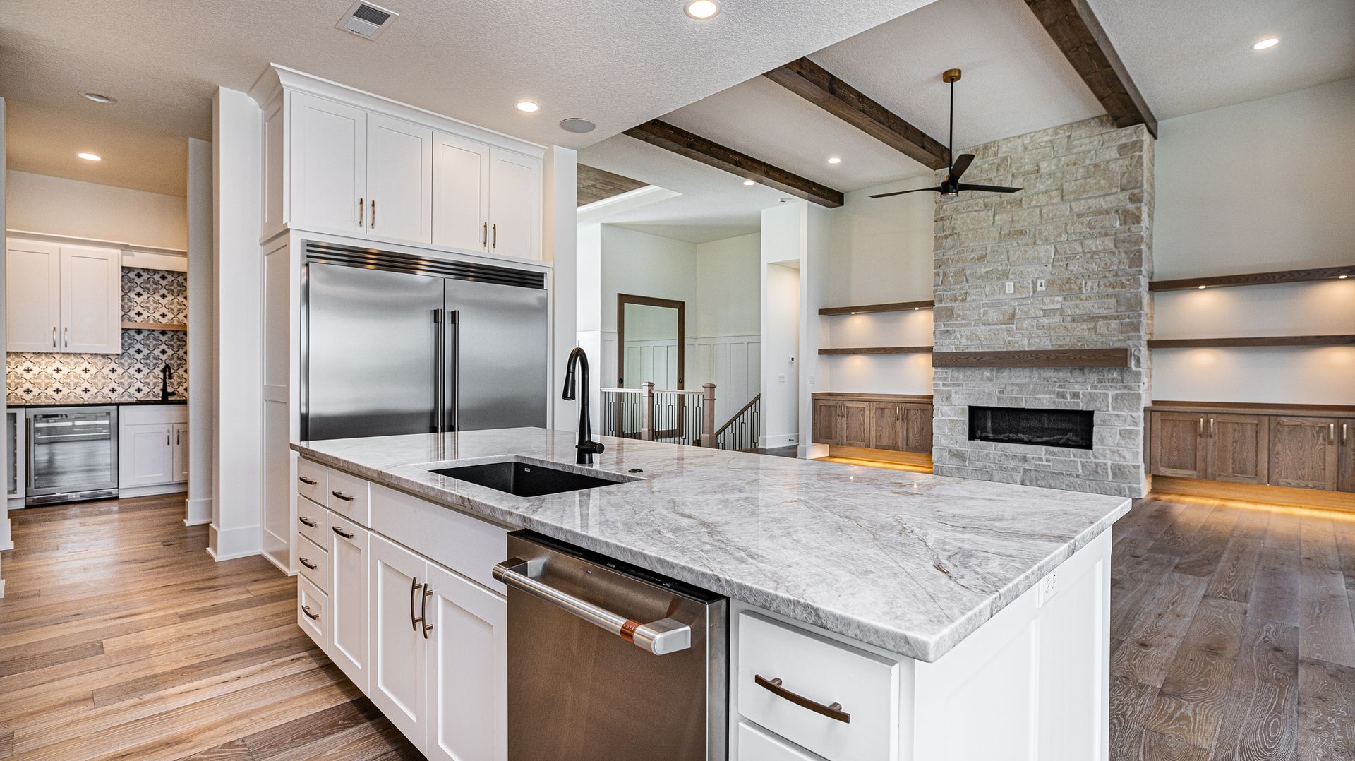 A kitchen with white cabinets , granite counter tops , stainless steel appliances and a large island.