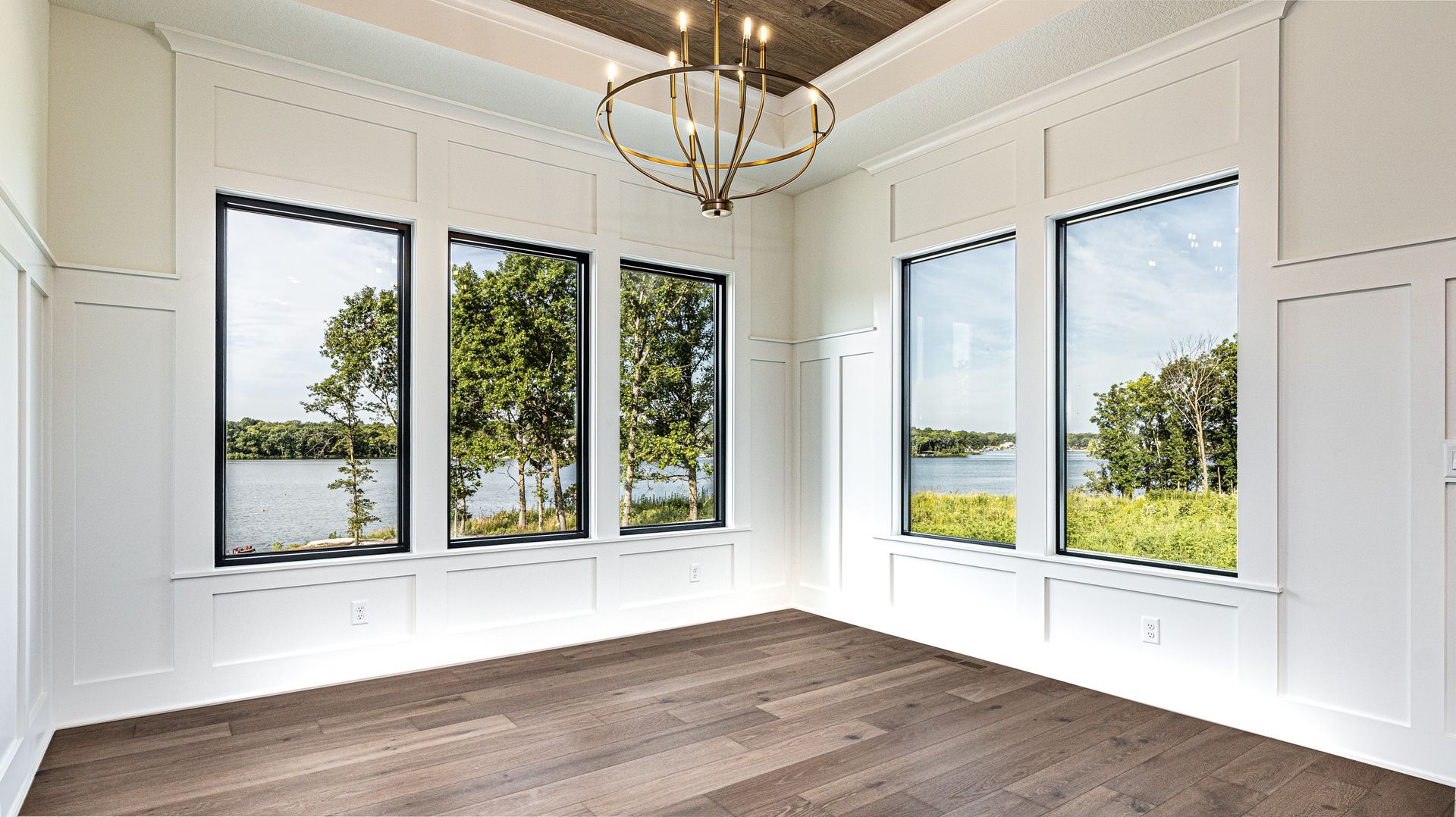 An empty room with a lot of windows and a chandelier.