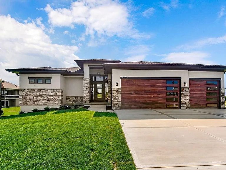 A modern house with a large driveway and a wooden garage door.