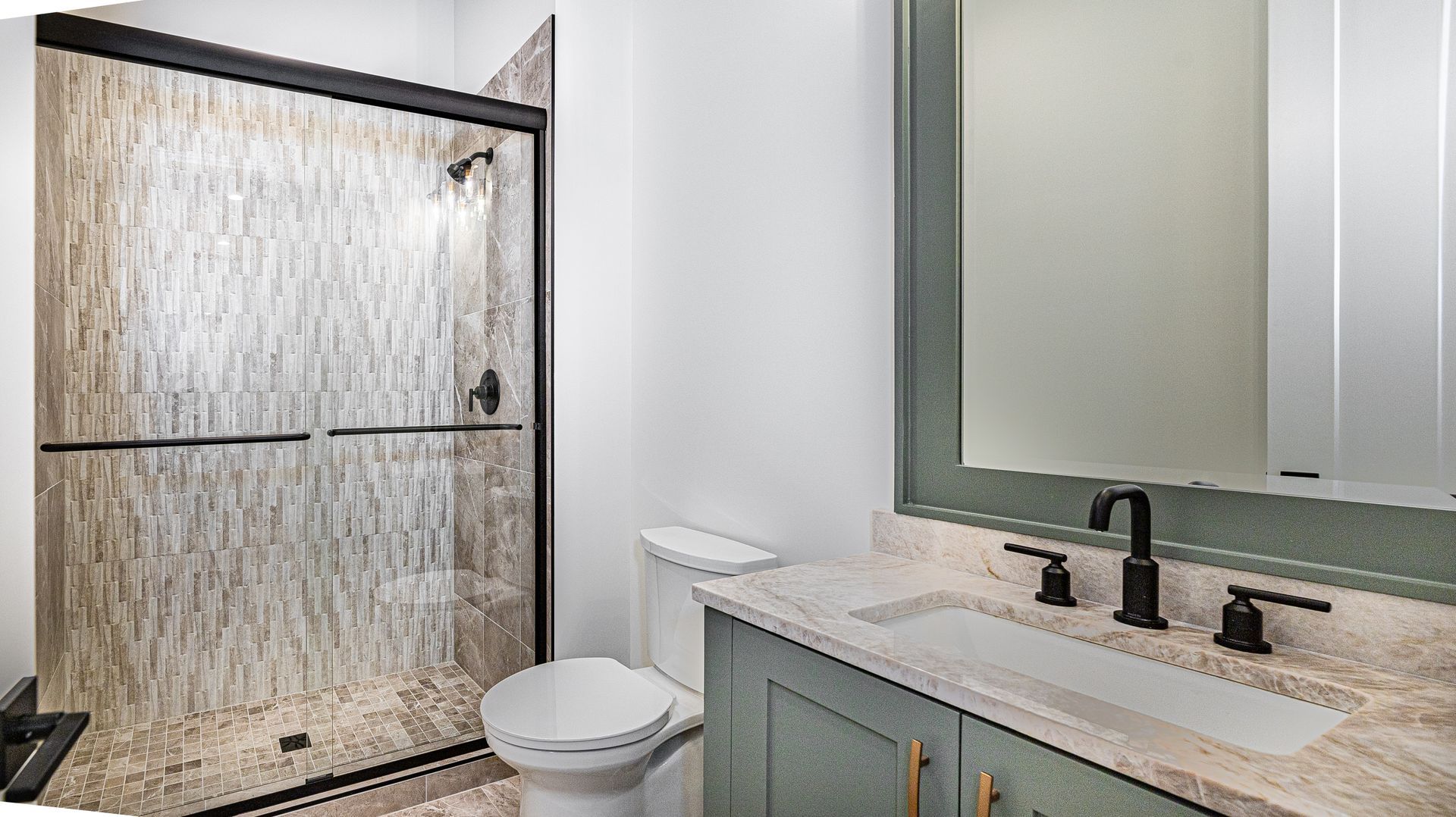 A bathroom with a toilet , sink , shower and mirror.