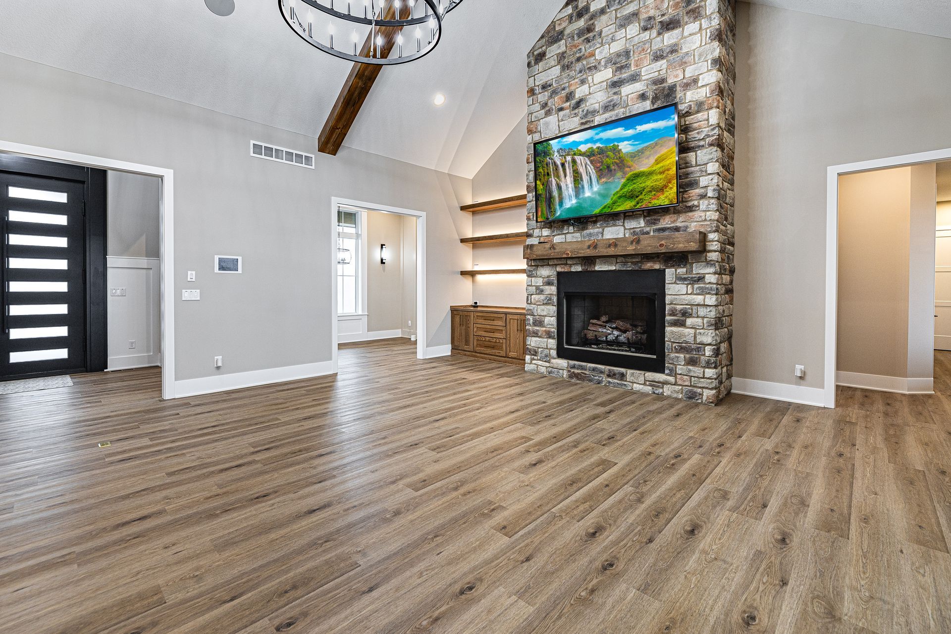 A living room with hardwood floors , a fireplace and a flat screen tv.