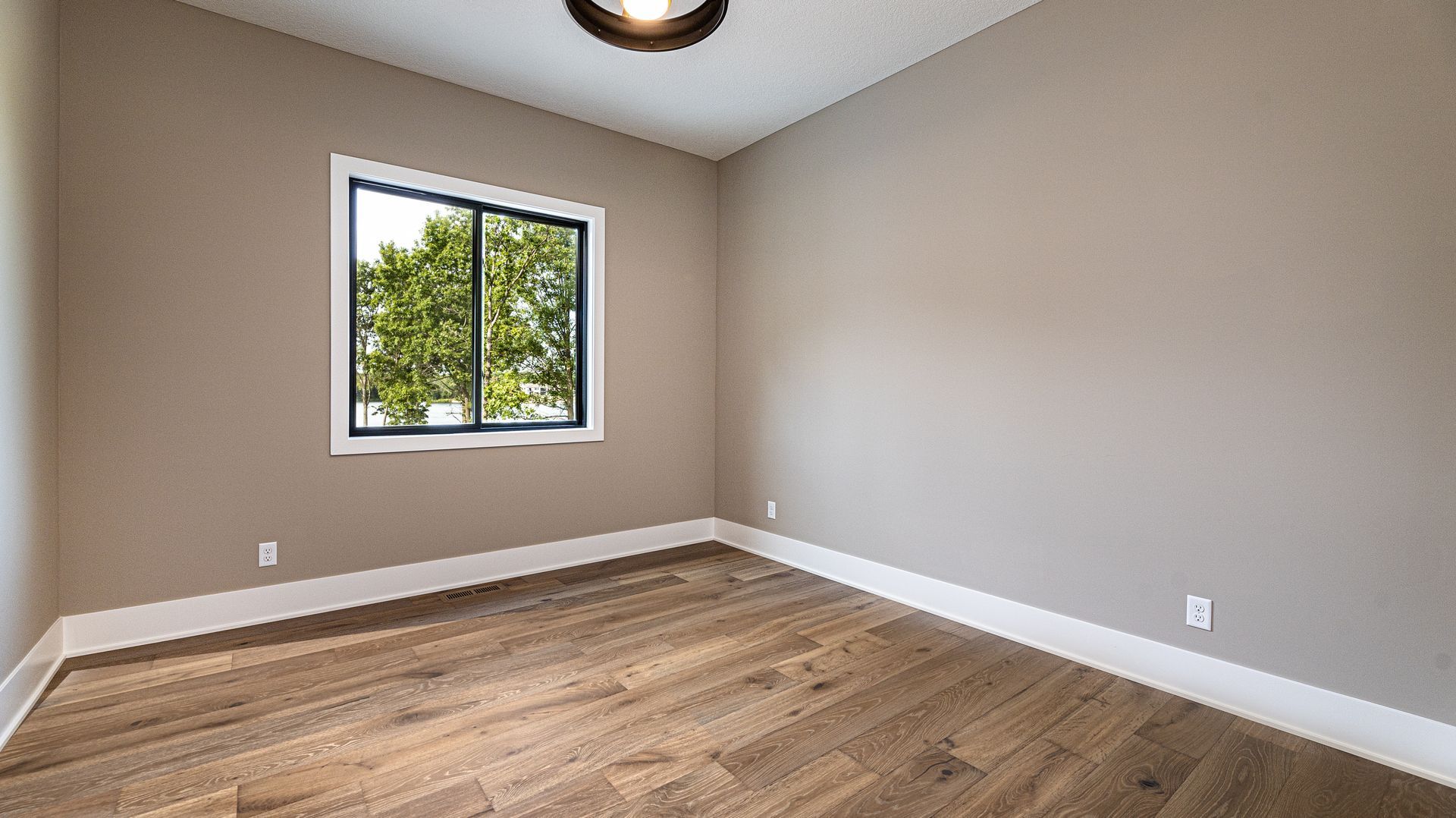 An empty room with hardwood floors and a window.