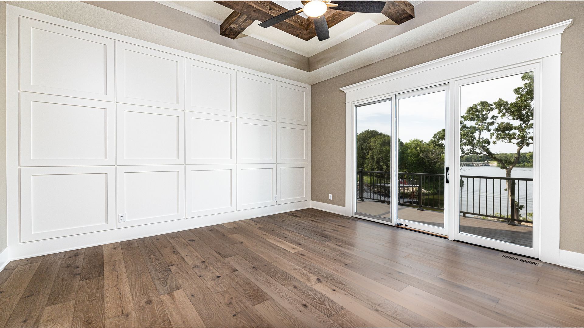 A large empty room with sliding glass doors and a ceiling fan.