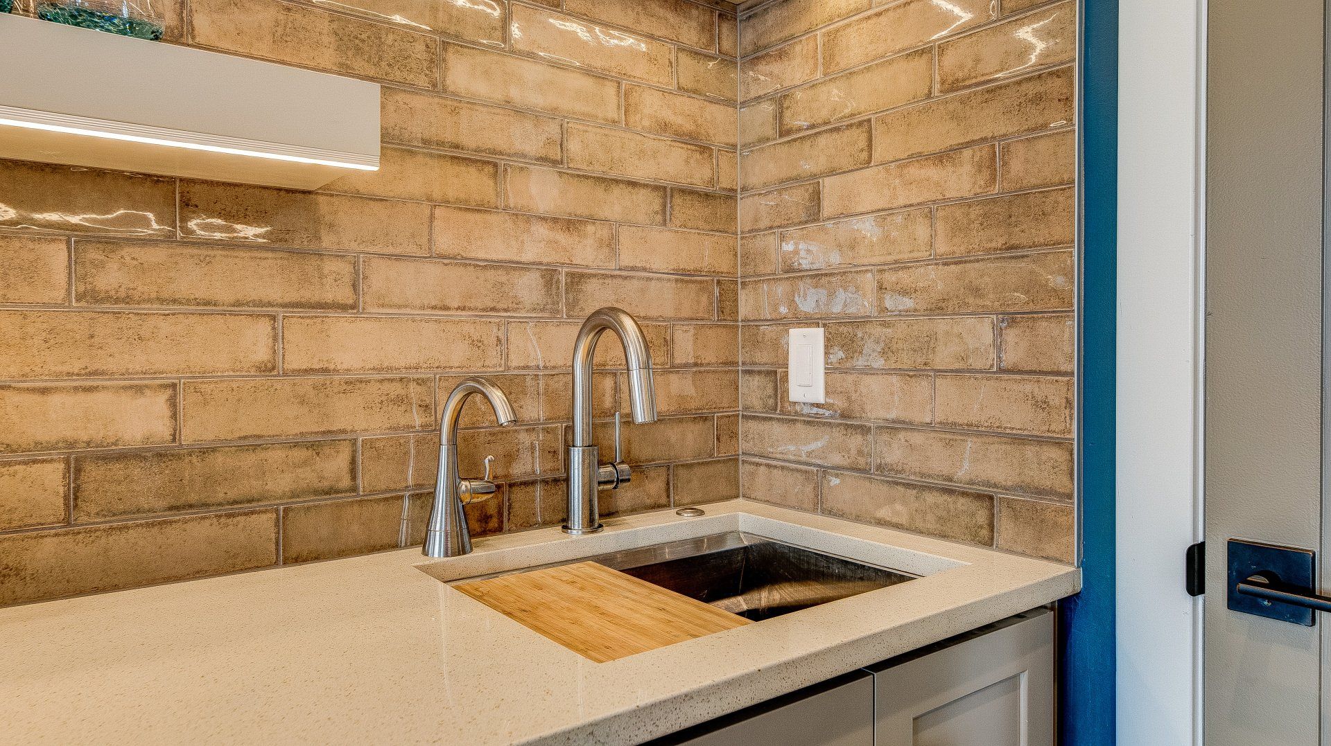 A kitchen with a sink and a brick wall.