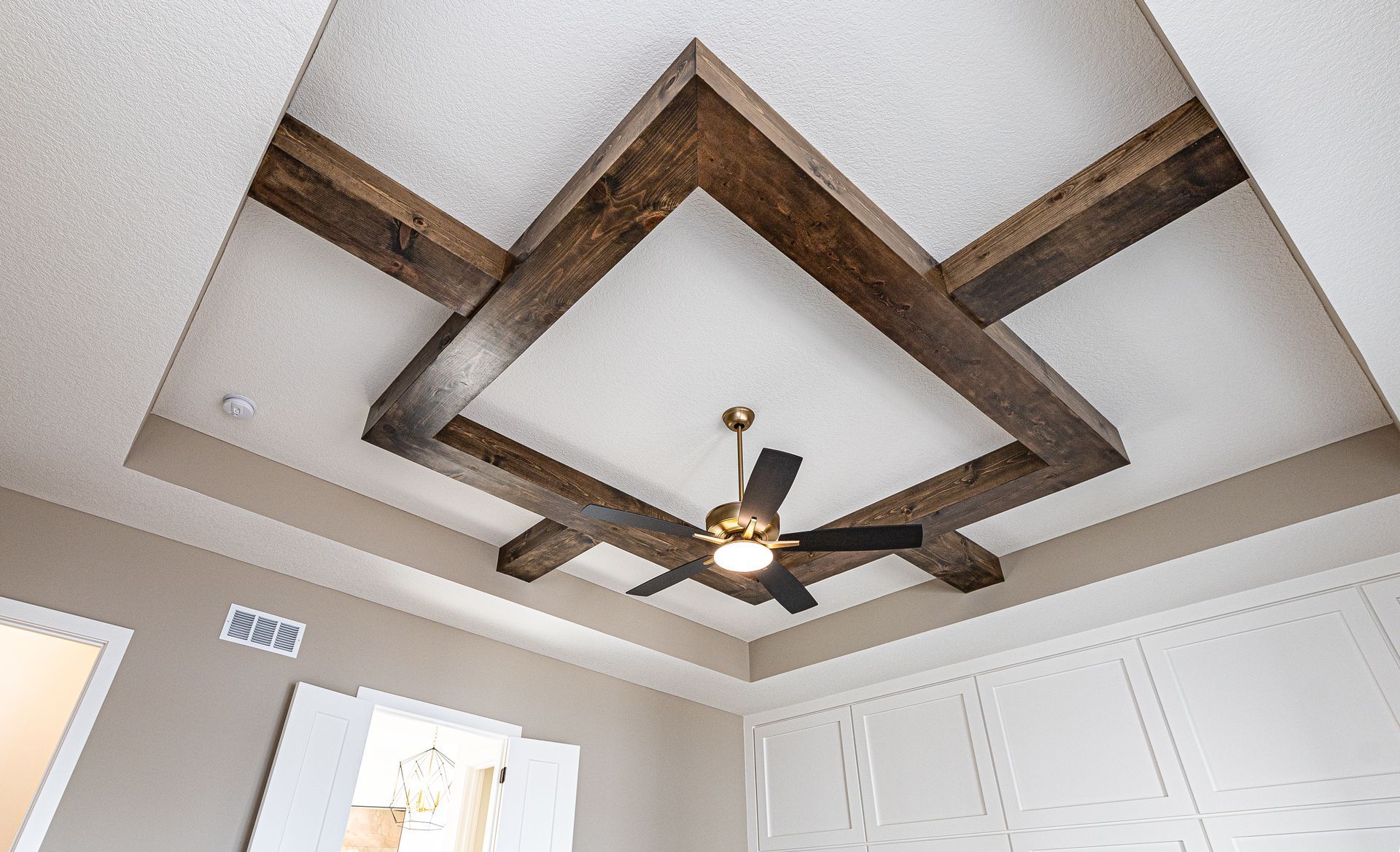 A ceiling with wooden beams and a ceiling fan in a room.