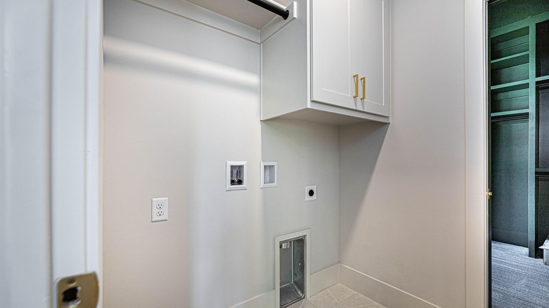A laundry room with white cabinets and a cat door.