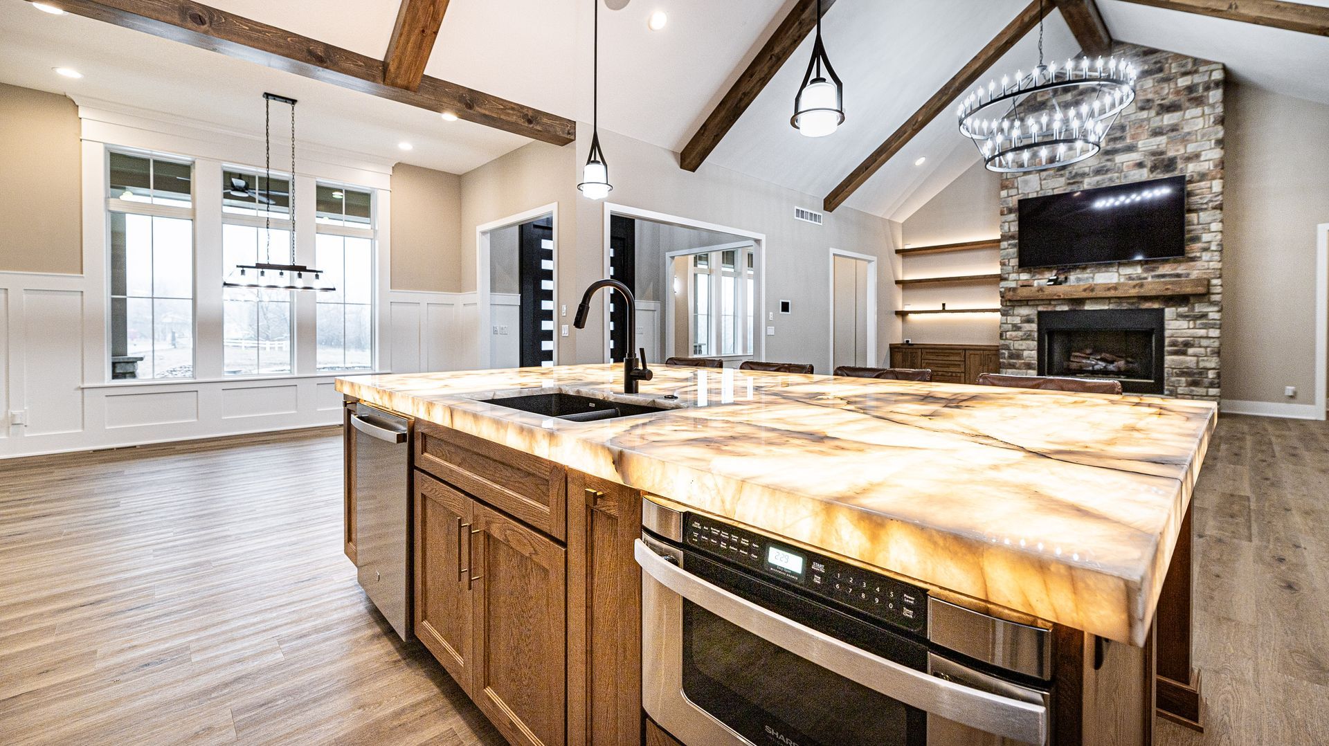 A kitchen with a large island , stove , sink , and television.