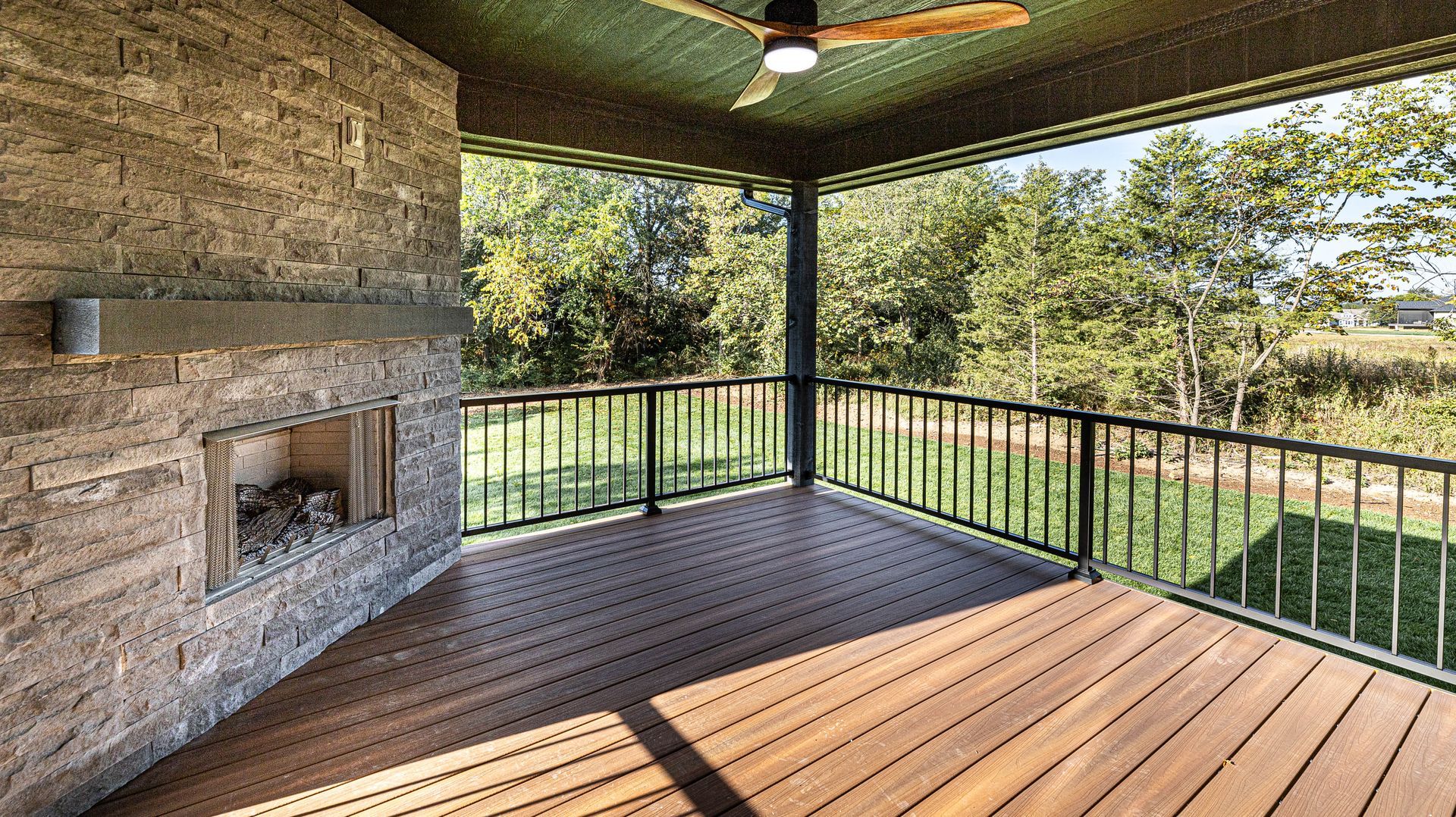 A screened in porch with a fireplace and a ceiling fan.