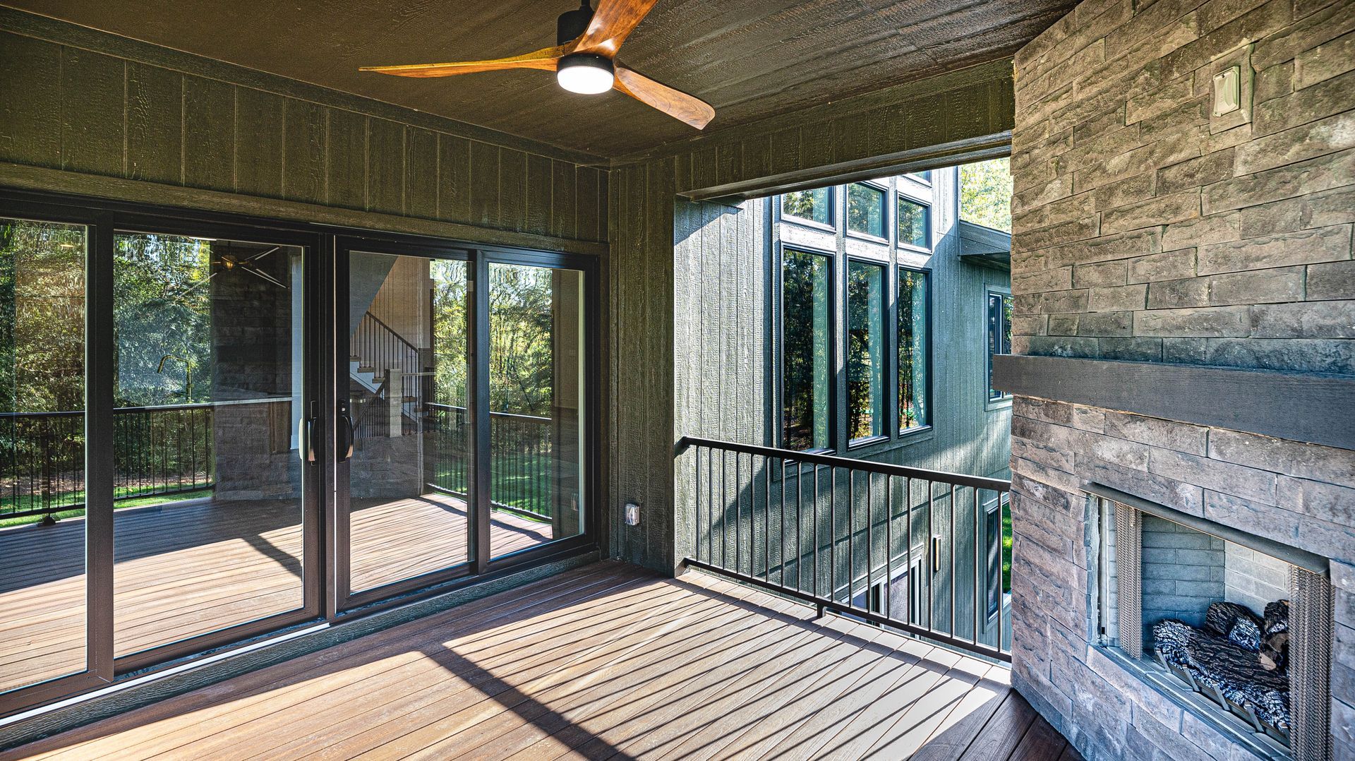 A screened in porch with a fireplace and a ceiling fan.