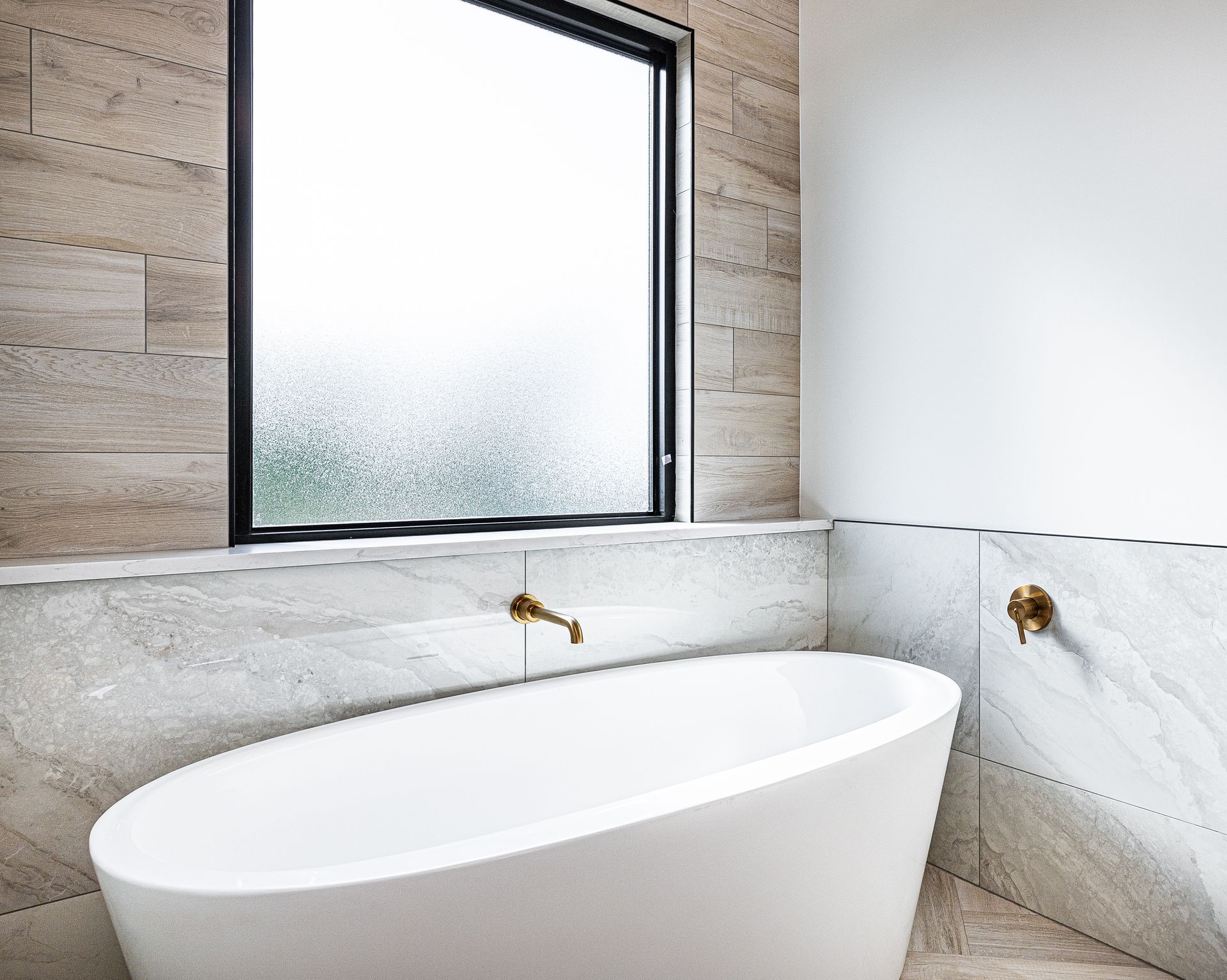 A bathtub in a bathroom next to a window.