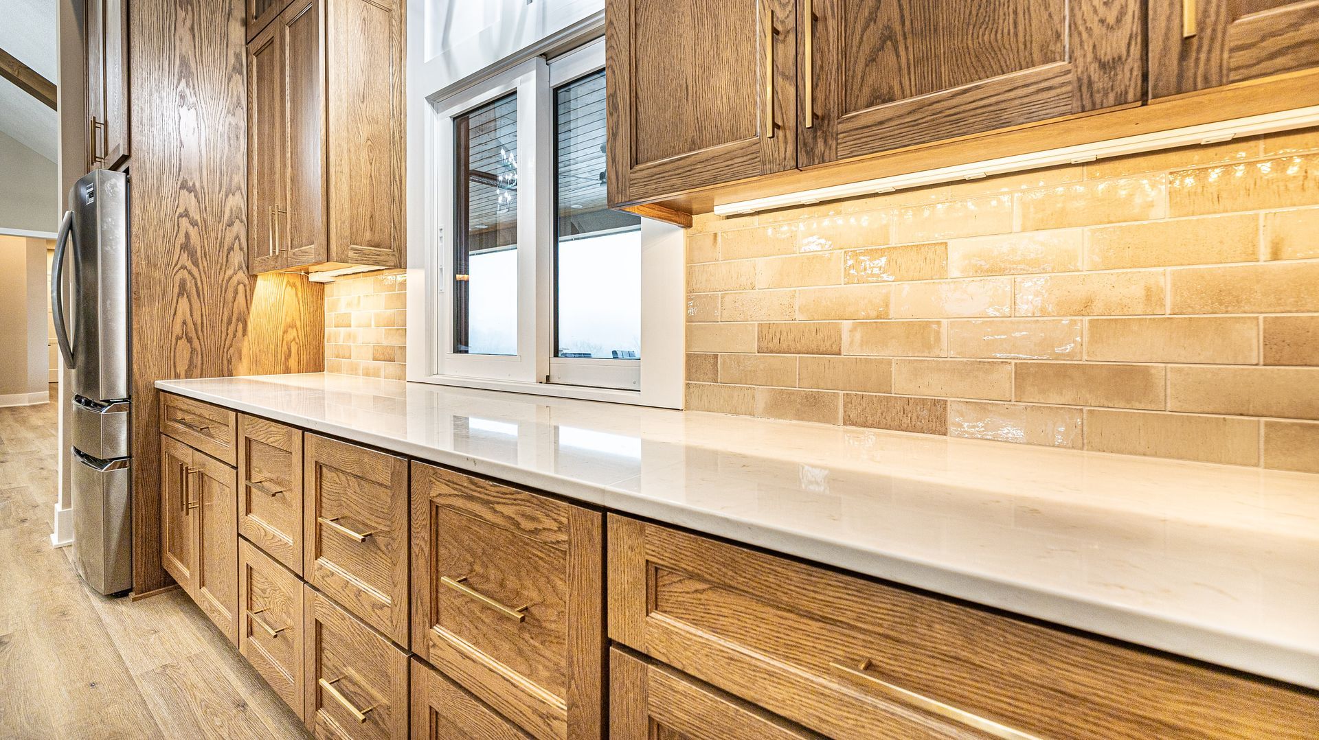 A kitchen with wooden cabinets and white counter tops.