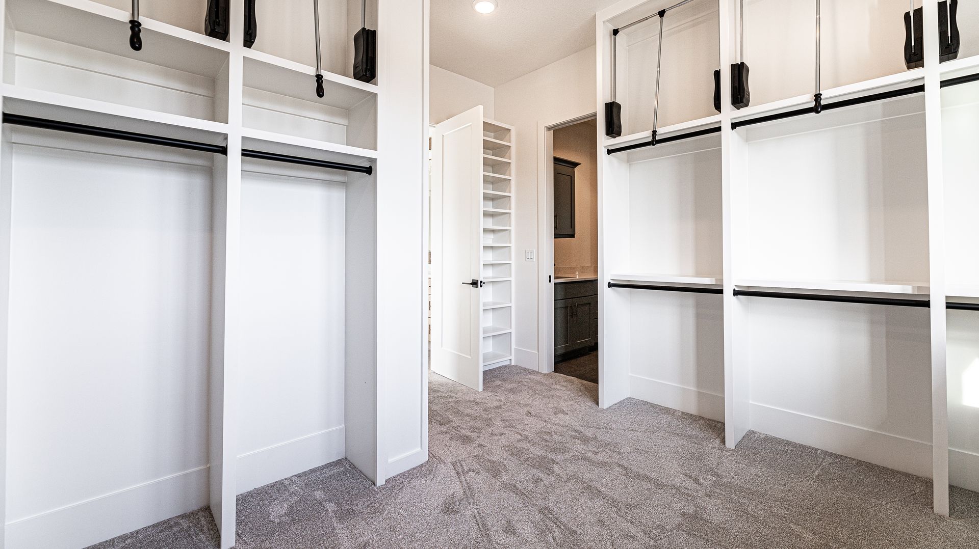 A walk in closet with lots of shelves and a carpeted floor.