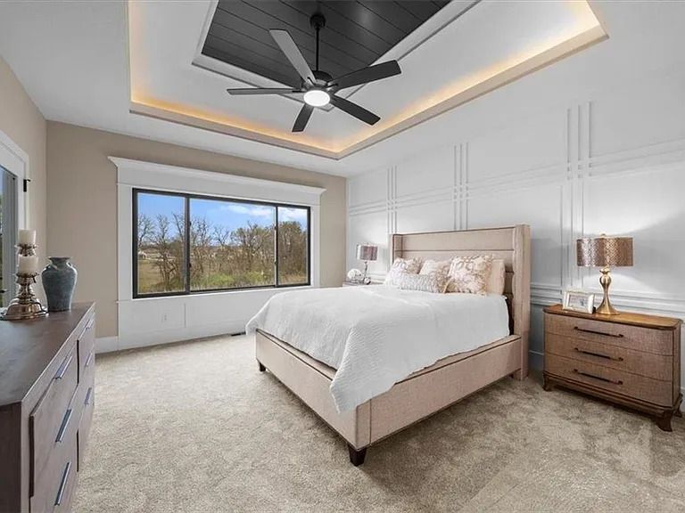 A bedroom with a large bed and a ceiling fan.