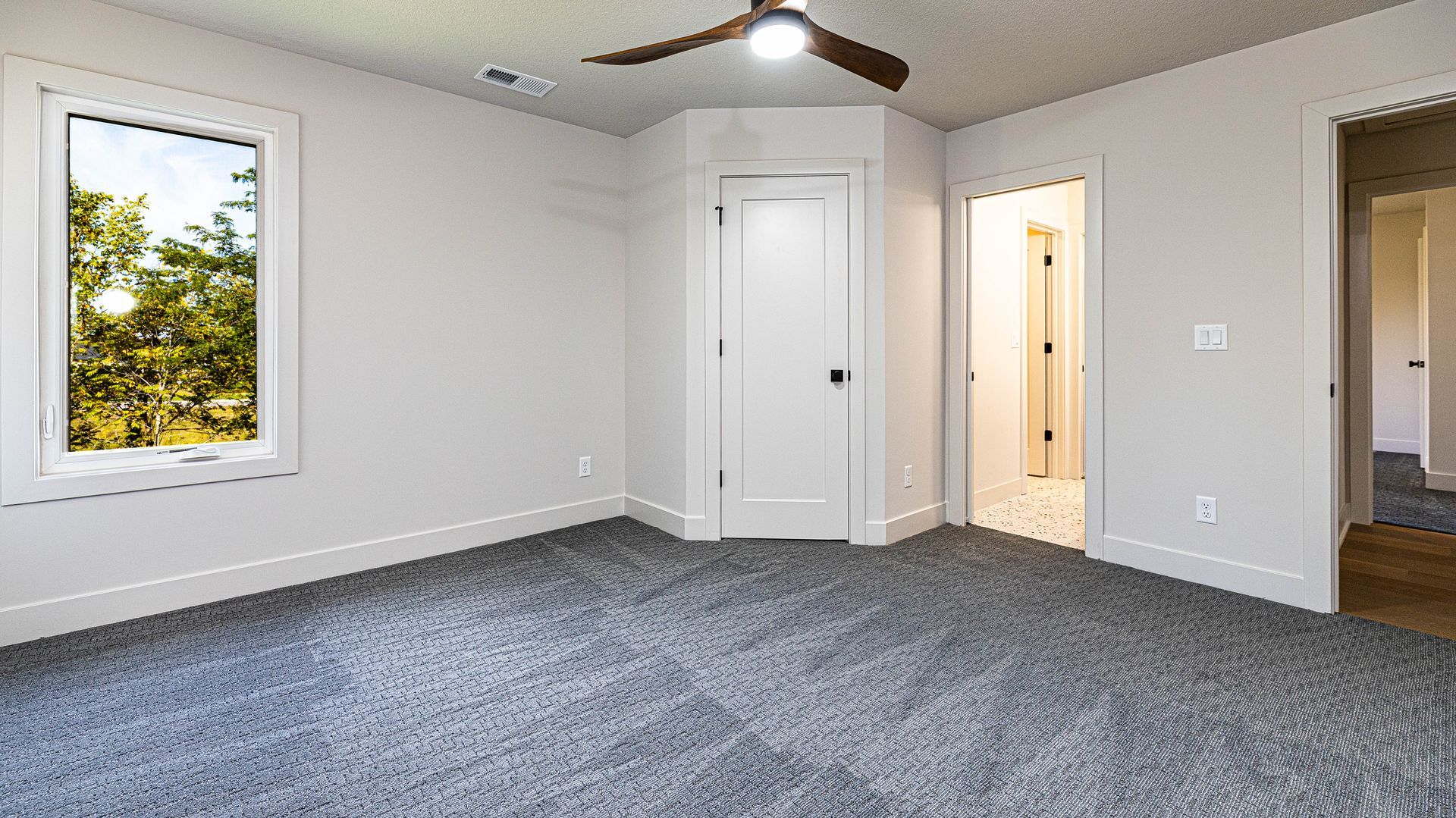An empty bedroom with a ceiling fan and a window.