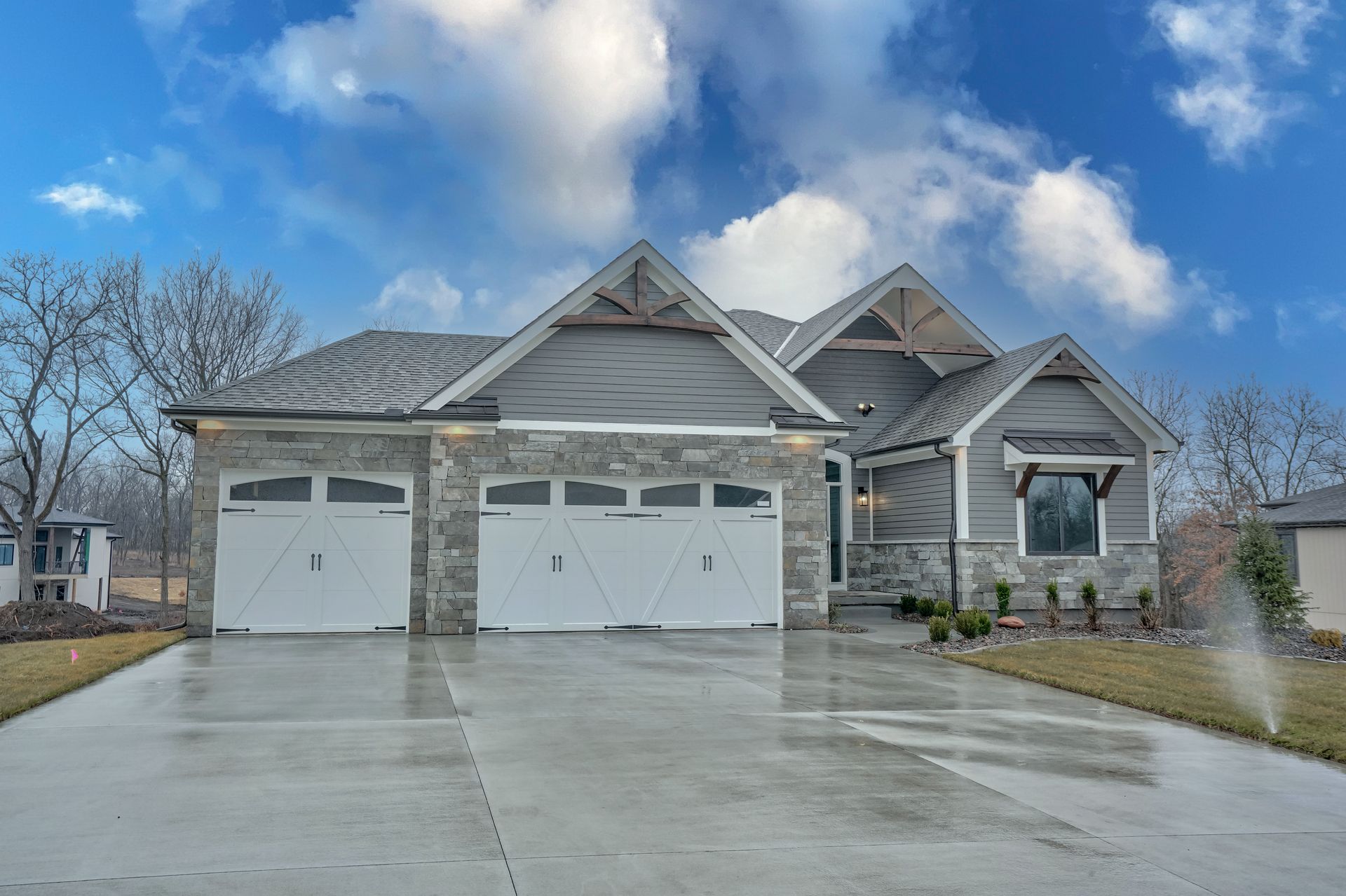 A large house with three garage doors and a concrete driveway.