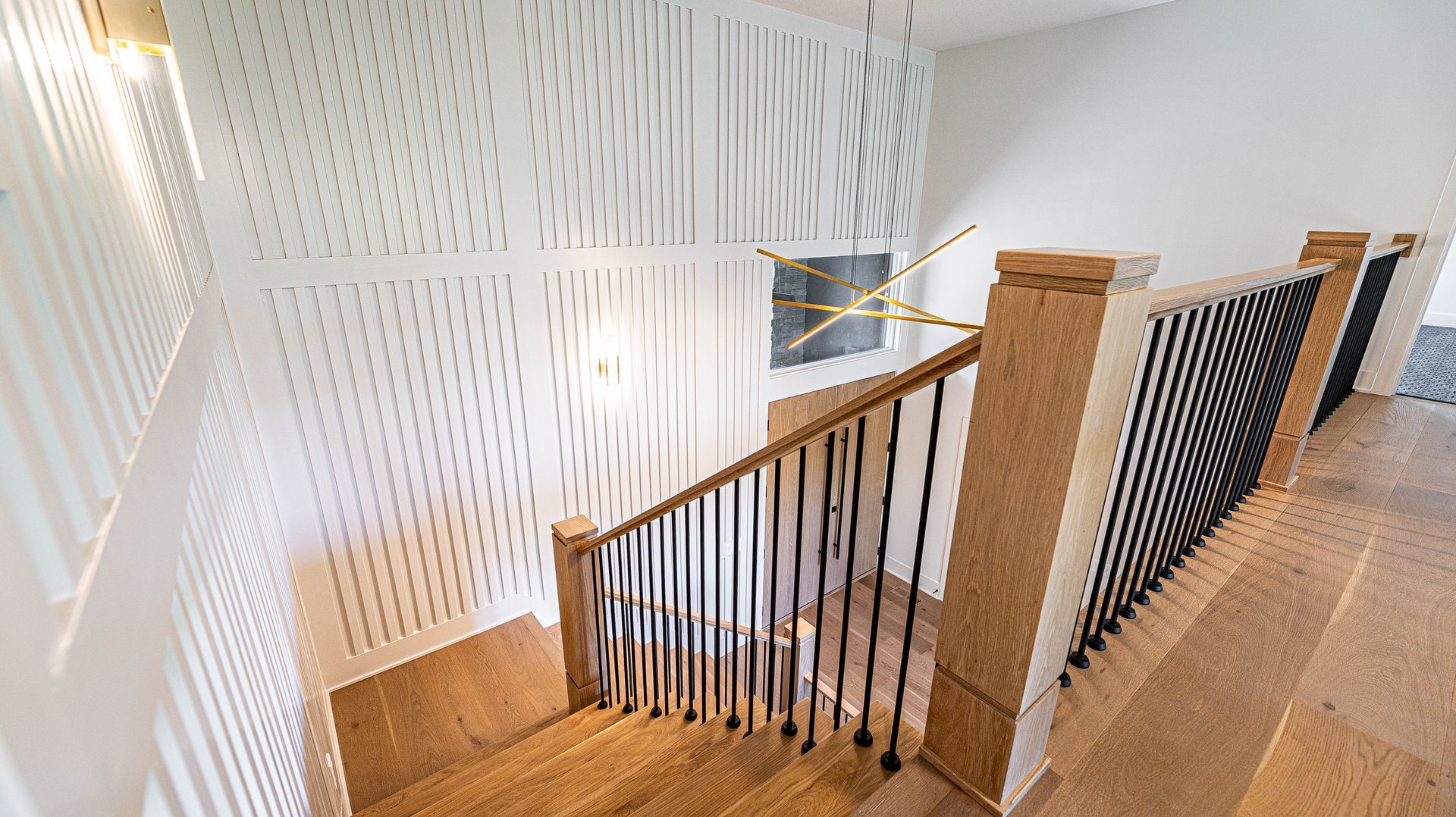 A wooden staircase with a black railing in a house.