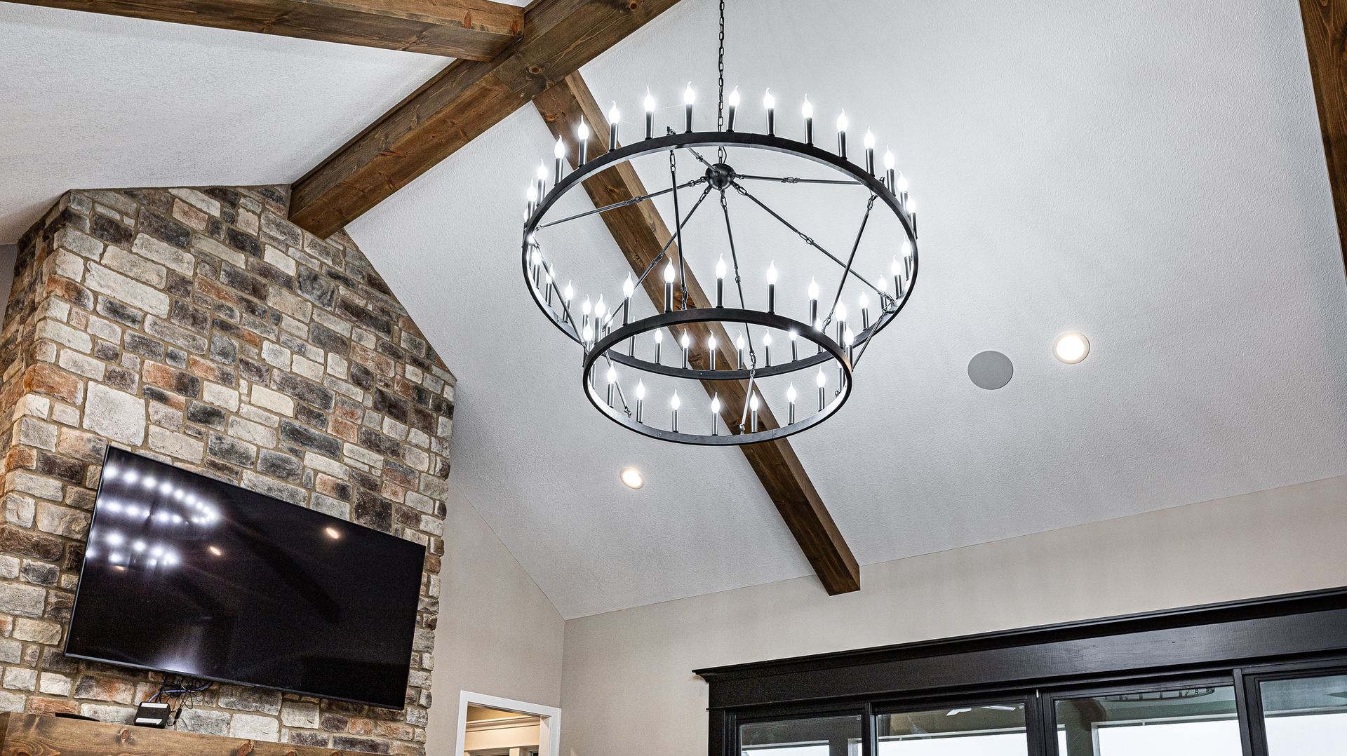 A living room with a chandelier hanging from the ceiling and a flat screen tv.