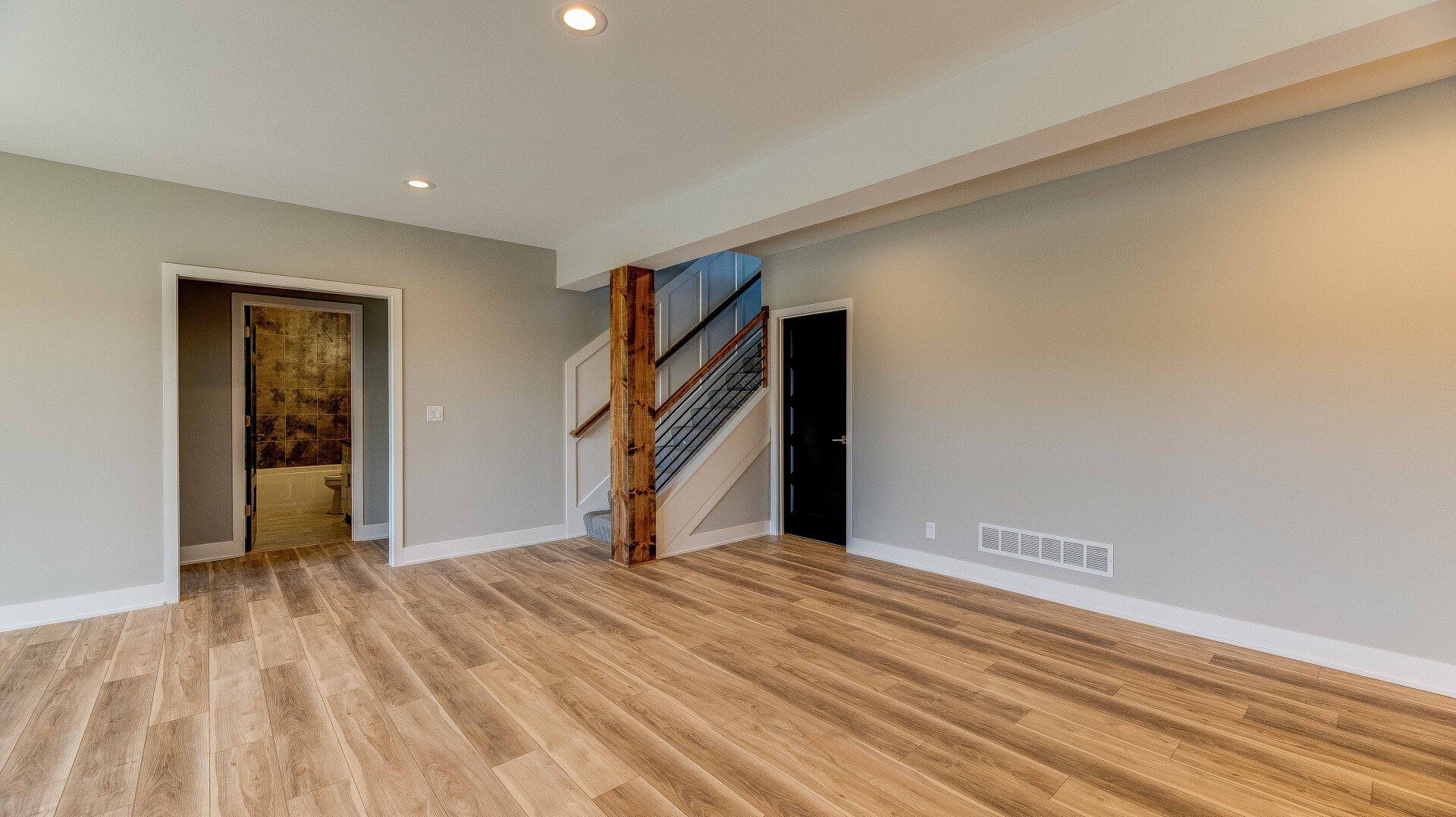 An empty living room with hardwood floors and a staircase.