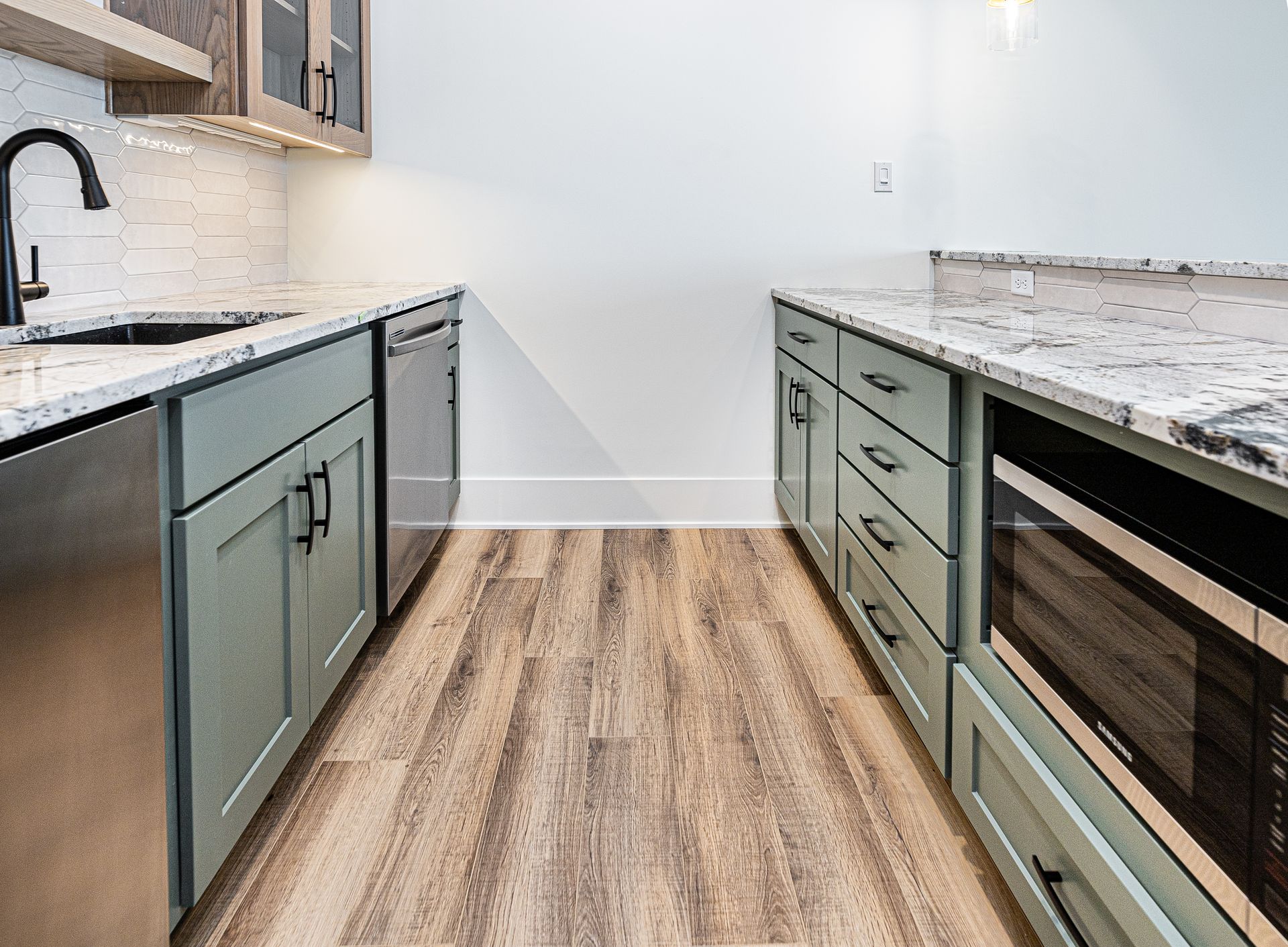 A kitchen with stainless steel appliances and wooden floors.