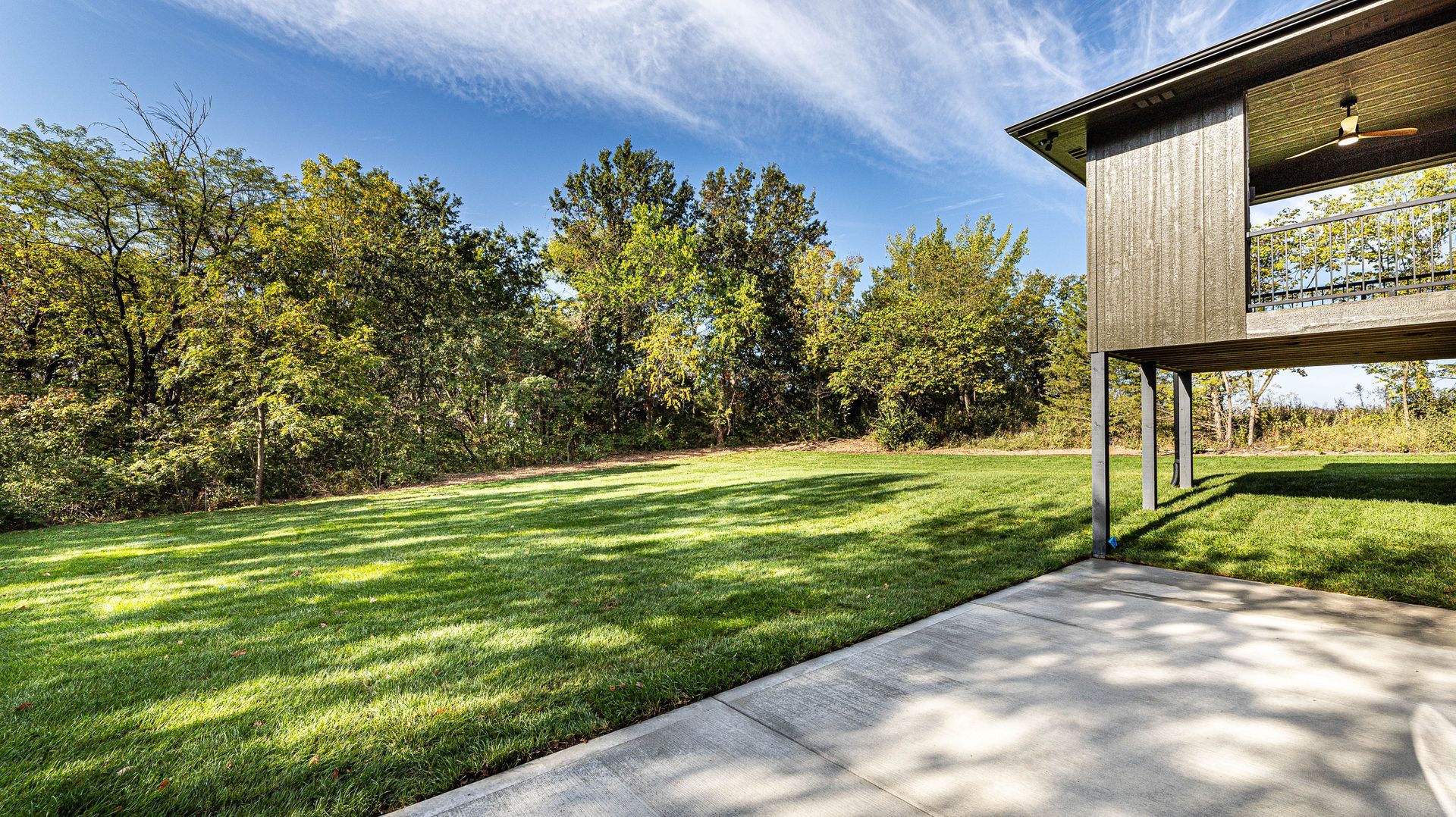 A large lawn with a house in the background and trees in the background.