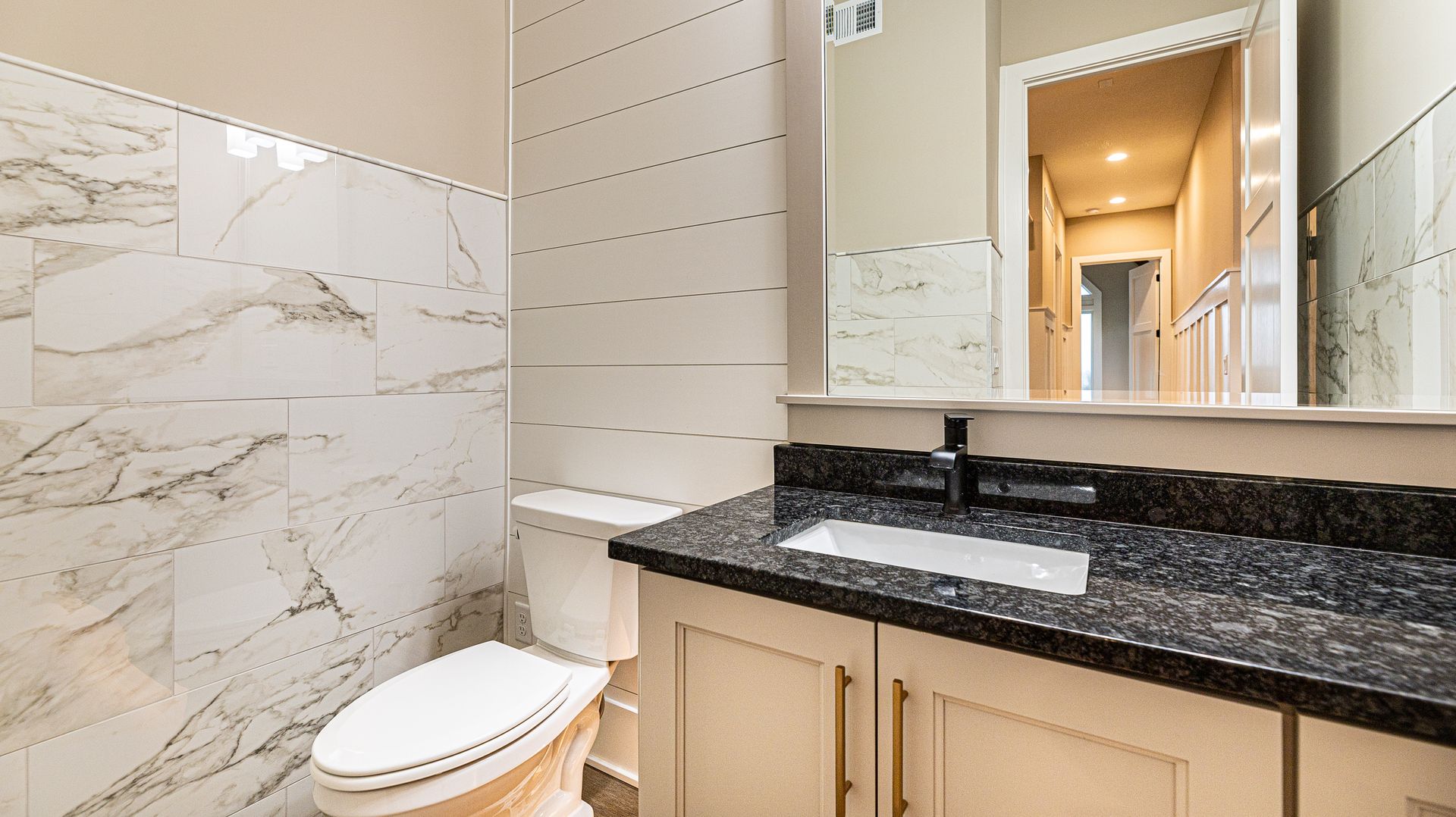 A bathroom with a toilet , sink and mirror.