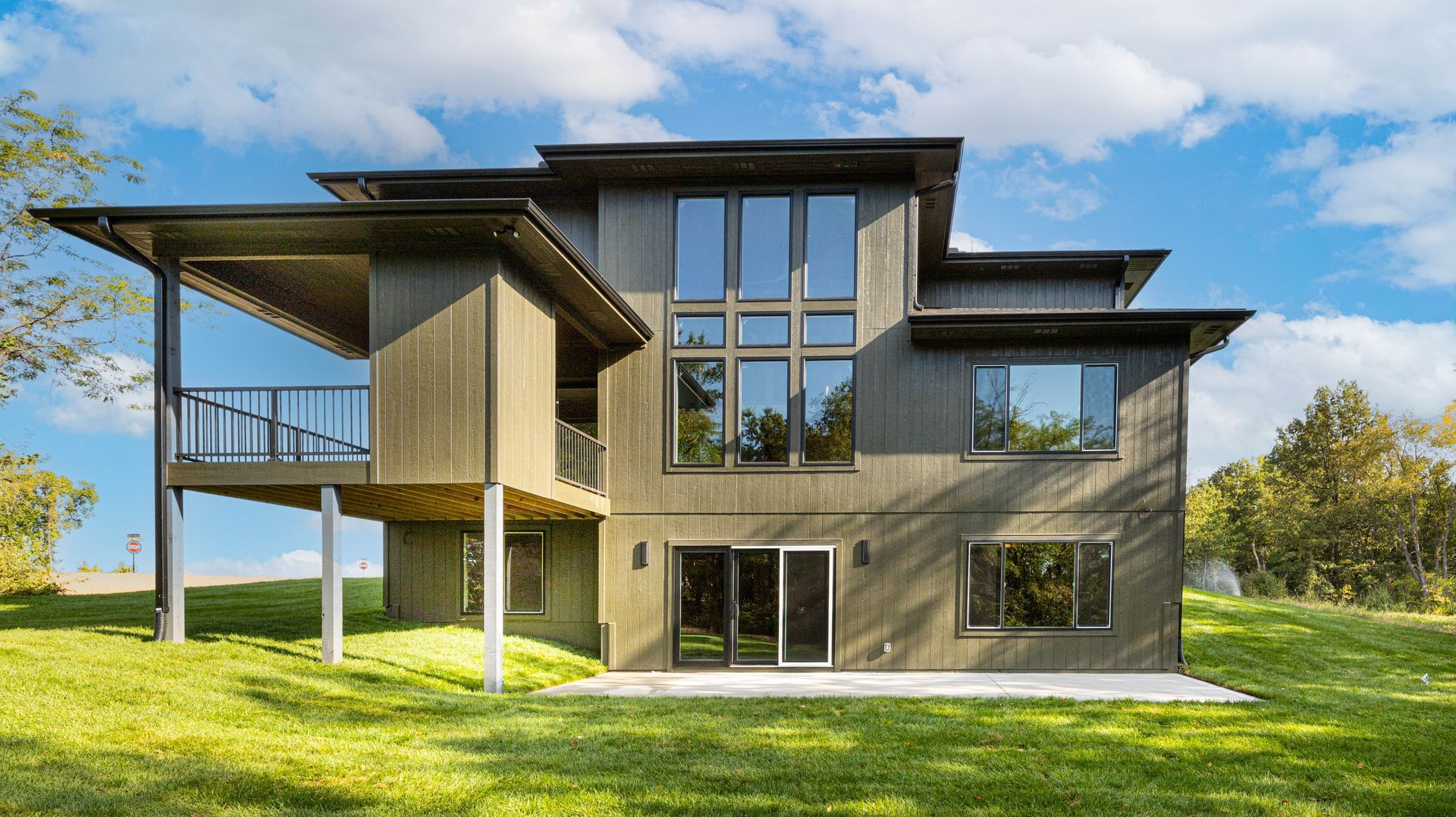 A large house with a lot of windows is sitting on top of a lush green hill.