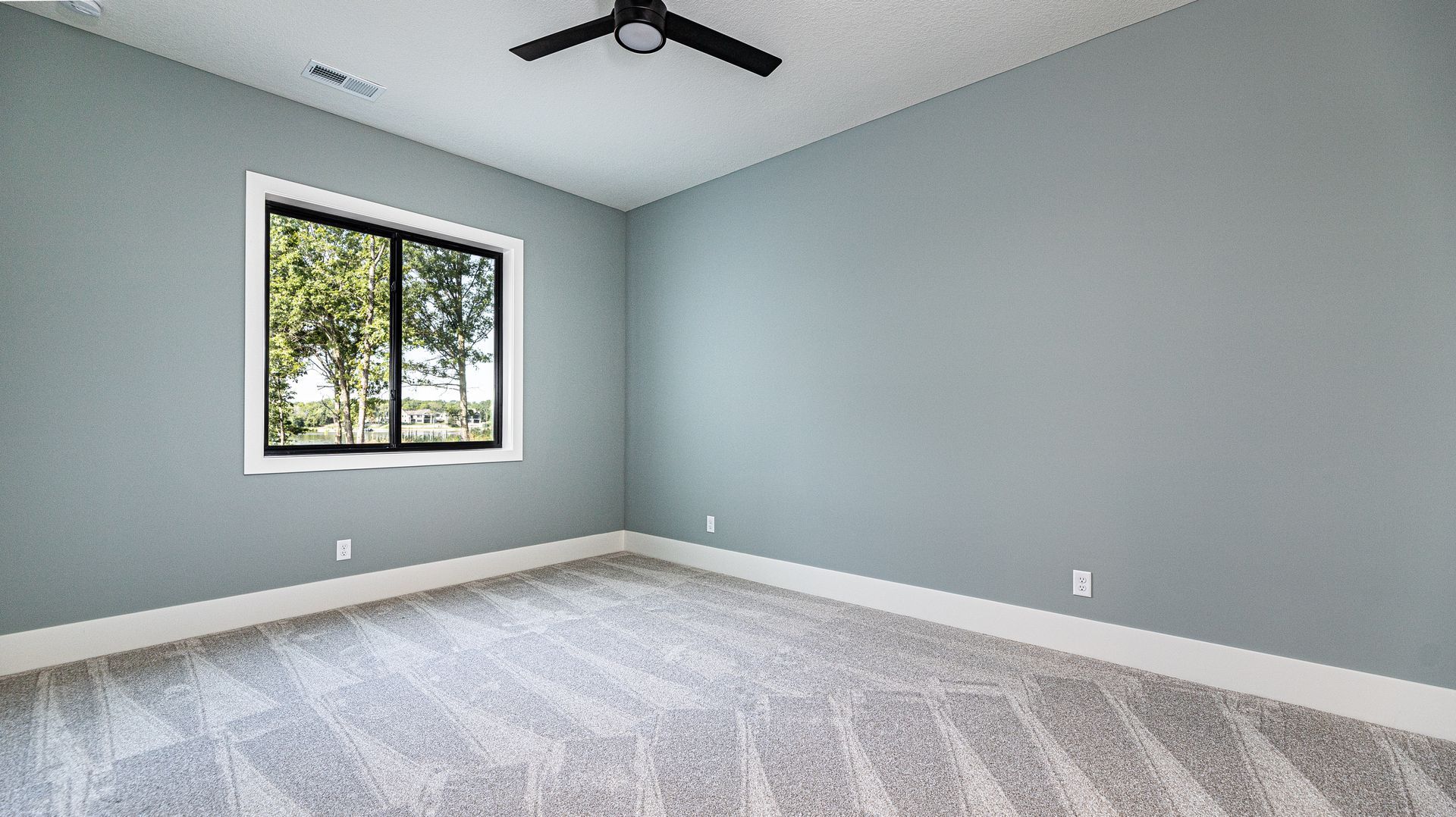 An empty bedroom with a ceiling fan and a window.