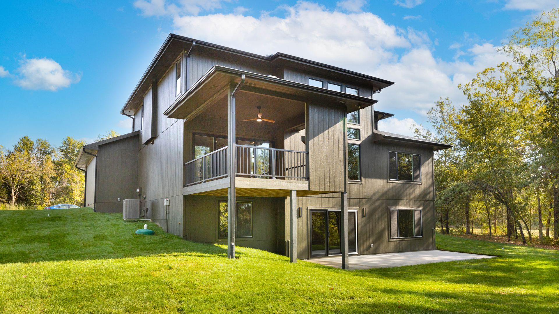 A large house is sitting on top of a lush green hill.