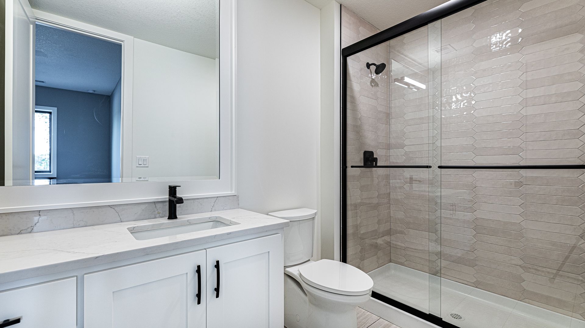 A bathroom with a toilet , sink , mirror and shower.