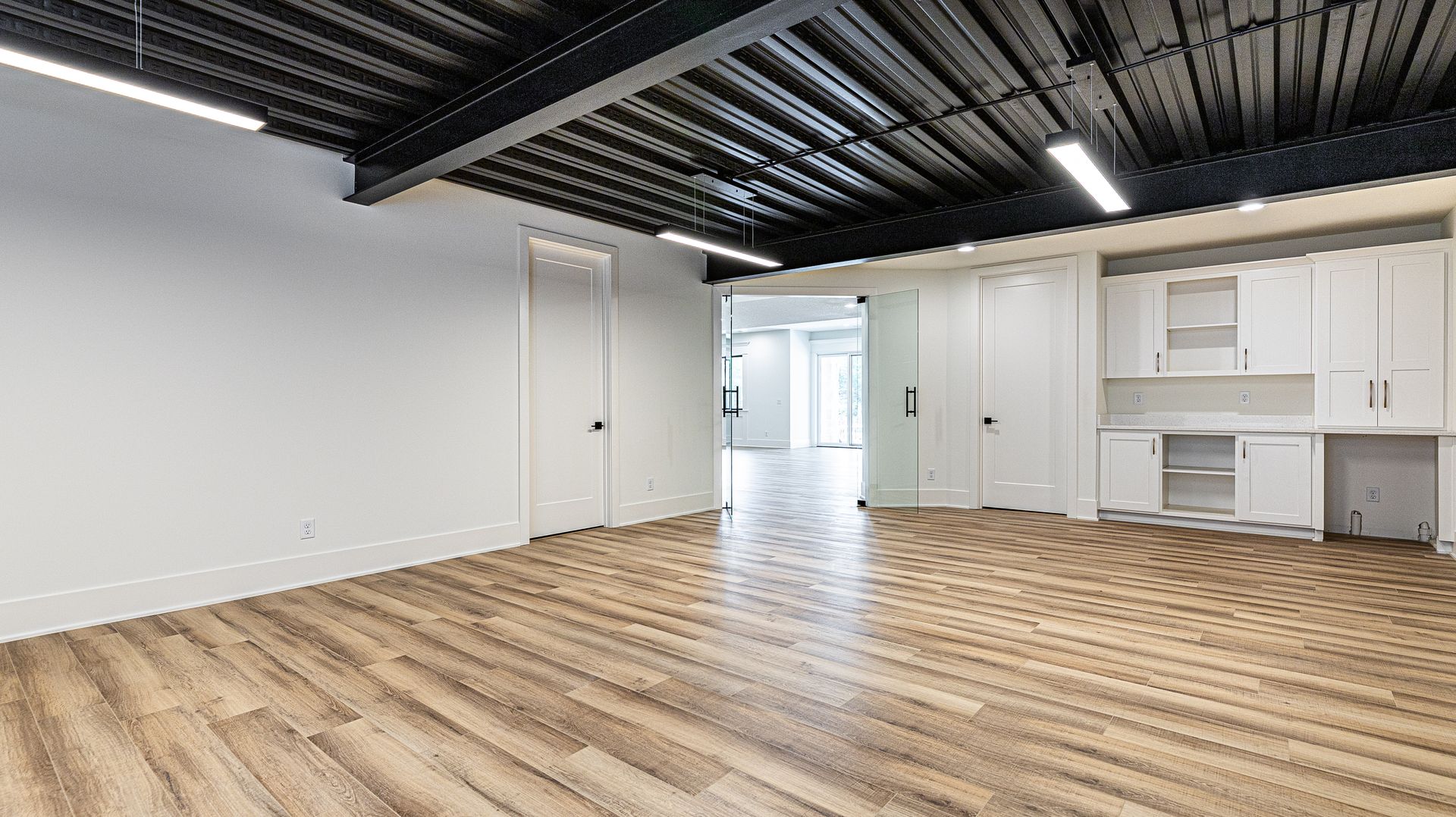 A large empty room with wooden floors and white cabinets.