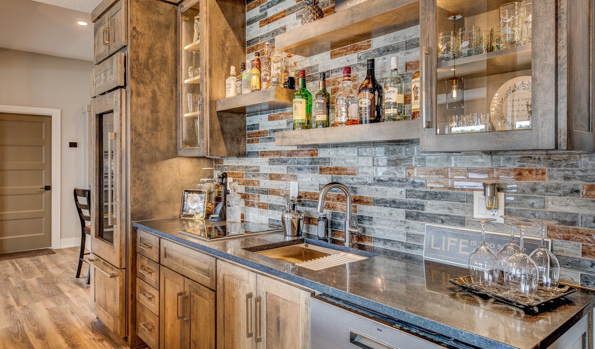 A kitchen with a bar and lots of bottles on shelves.