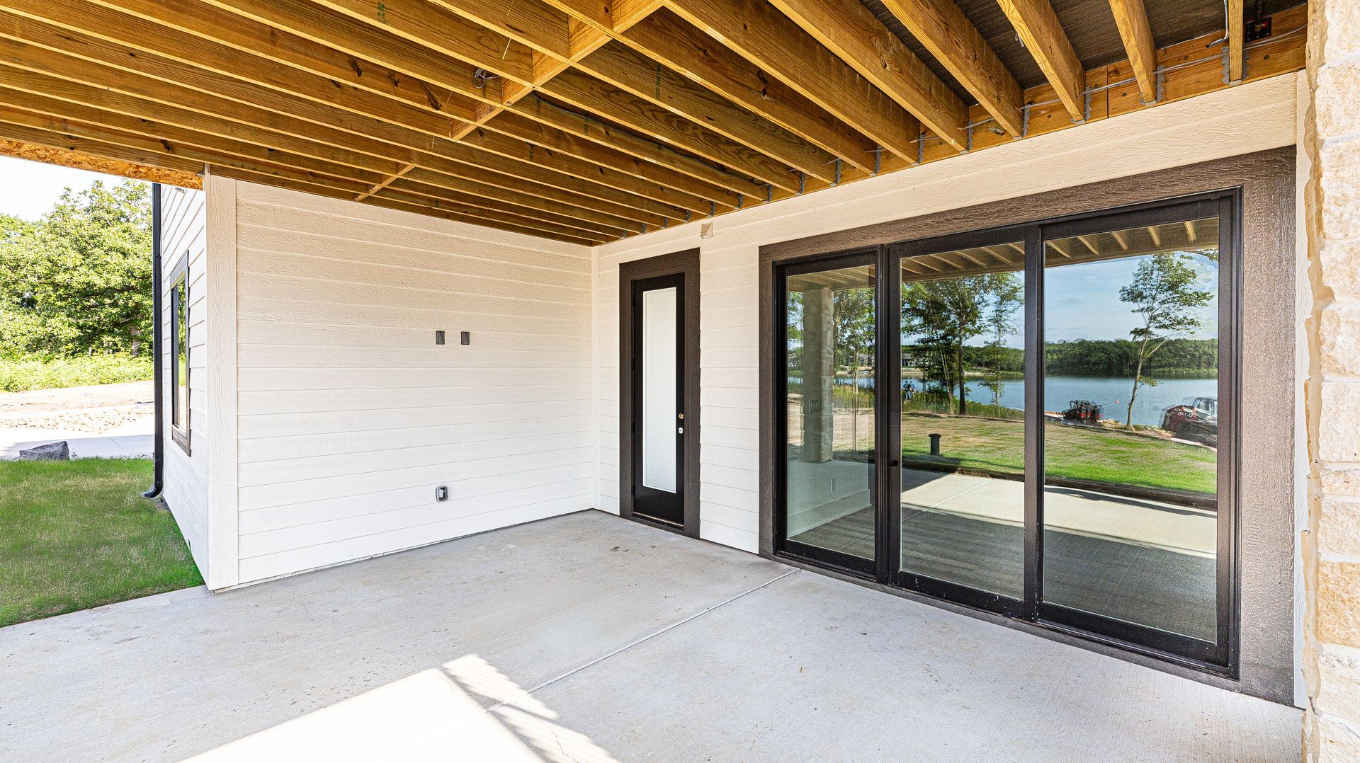 A large patio with sliding glass doors and a wooden ceiling.