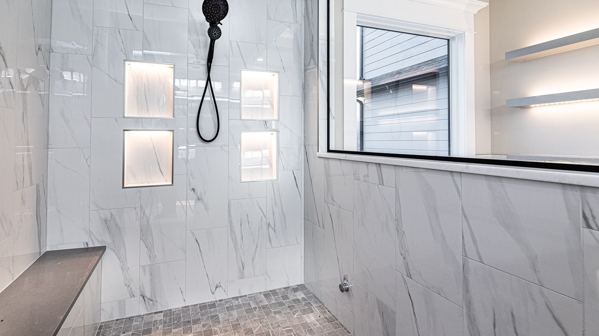 A bathroom with a shower head hanging from the ceiling and a window.