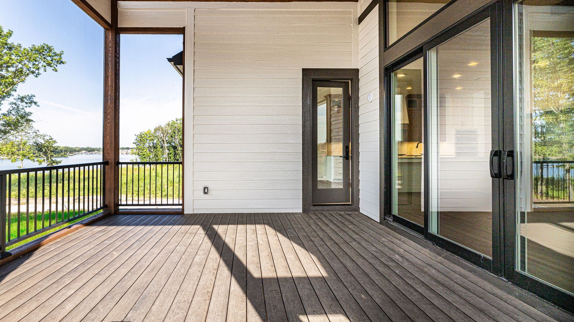 A large deck with sliding glass doors and a view of a lake.