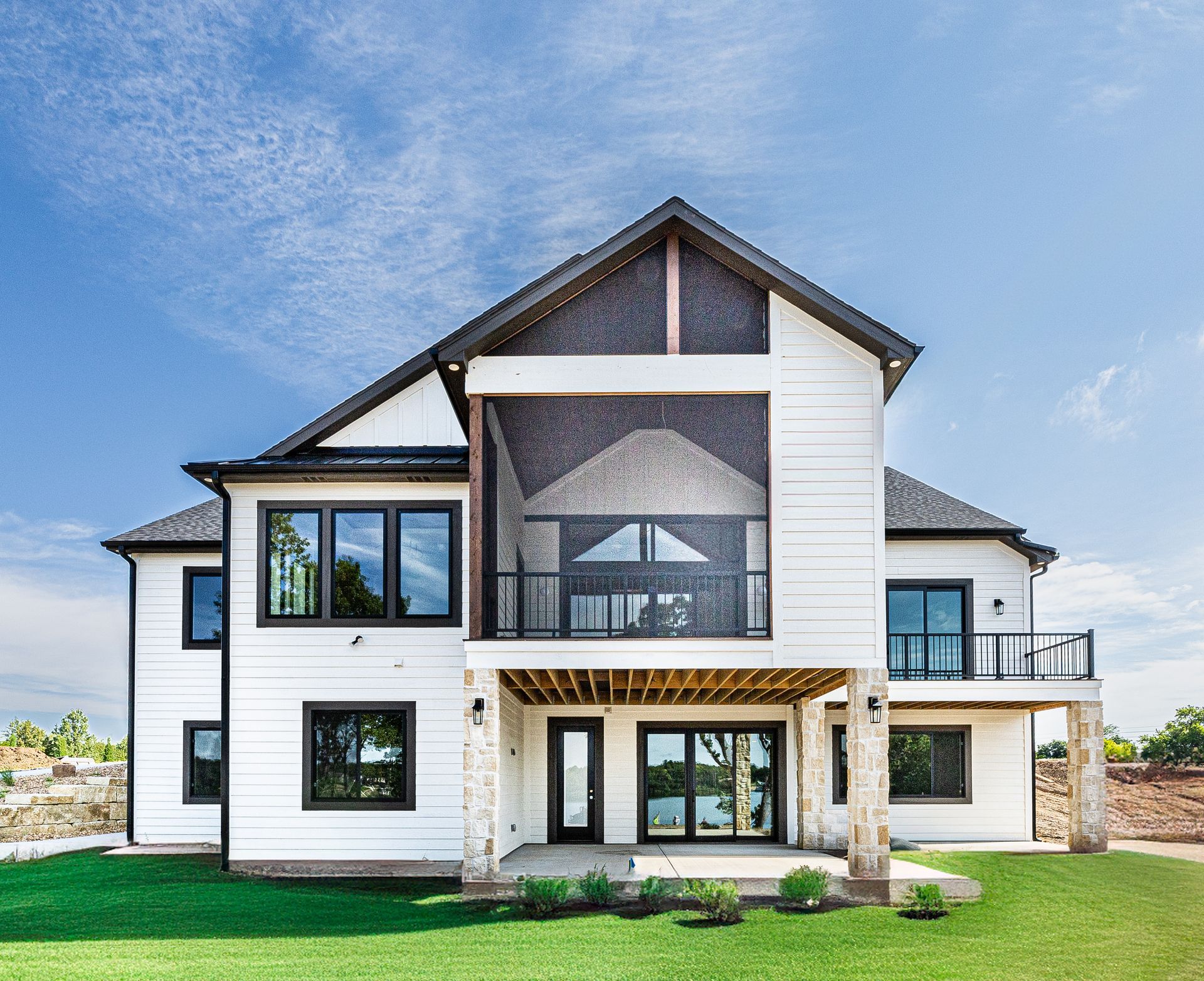 A large white house with a lot of windows is sitting on top of a lush green lawn.