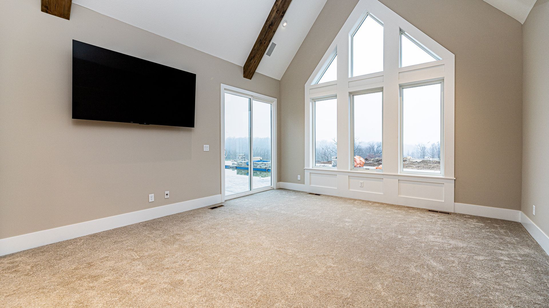 A living room with a flat screen tv on the wall and a lot of windows.