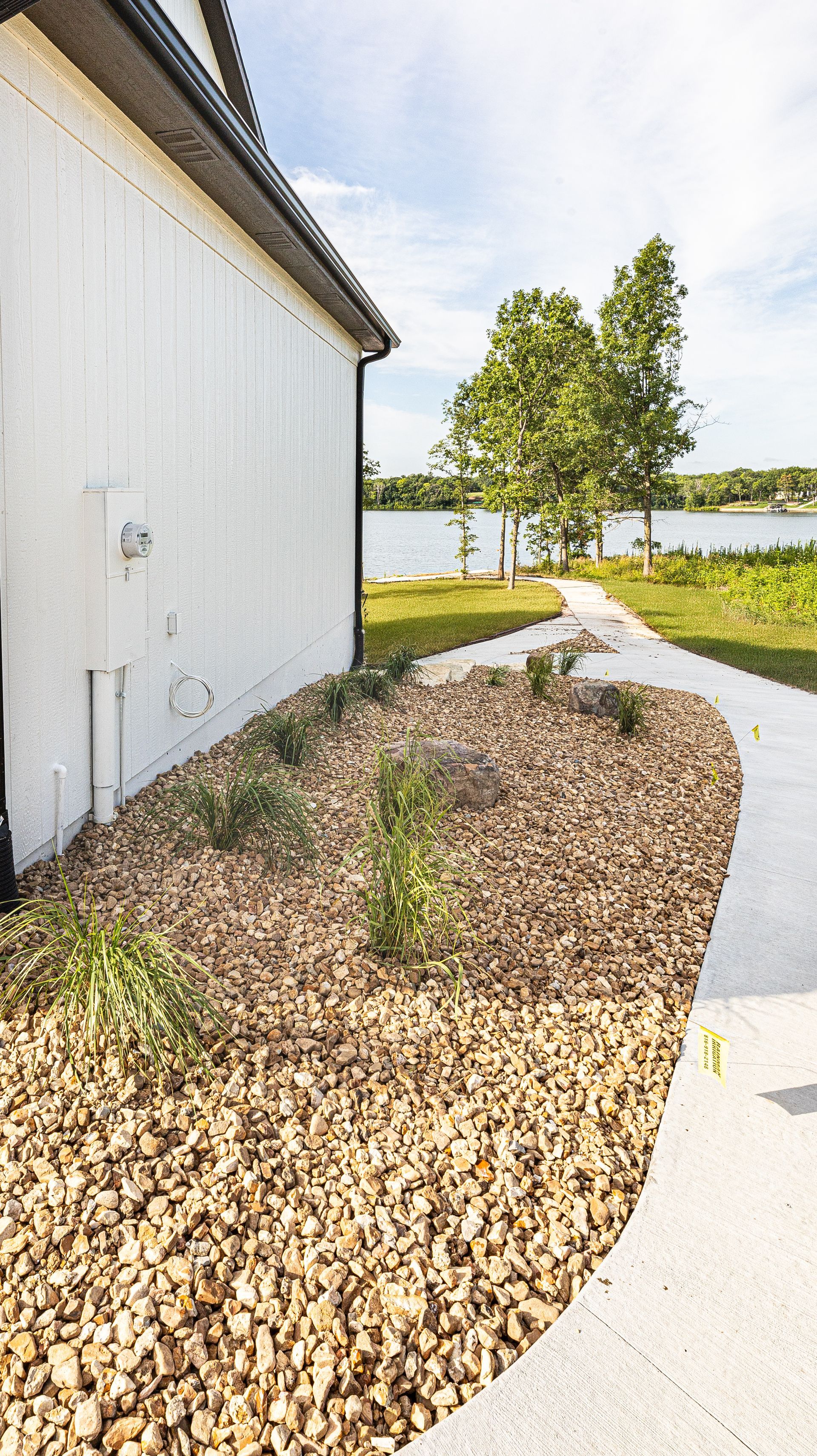 A white building with a walkway leading to a lake.